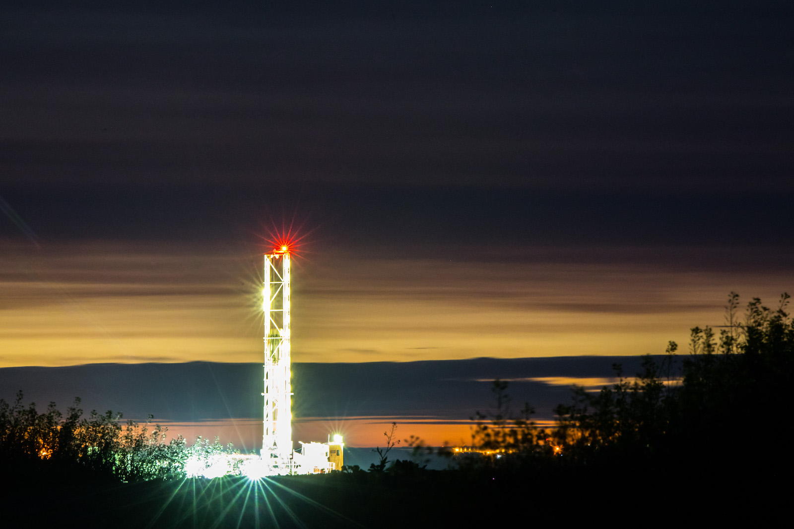 An oil rig at nighttime, lit with bright lights.