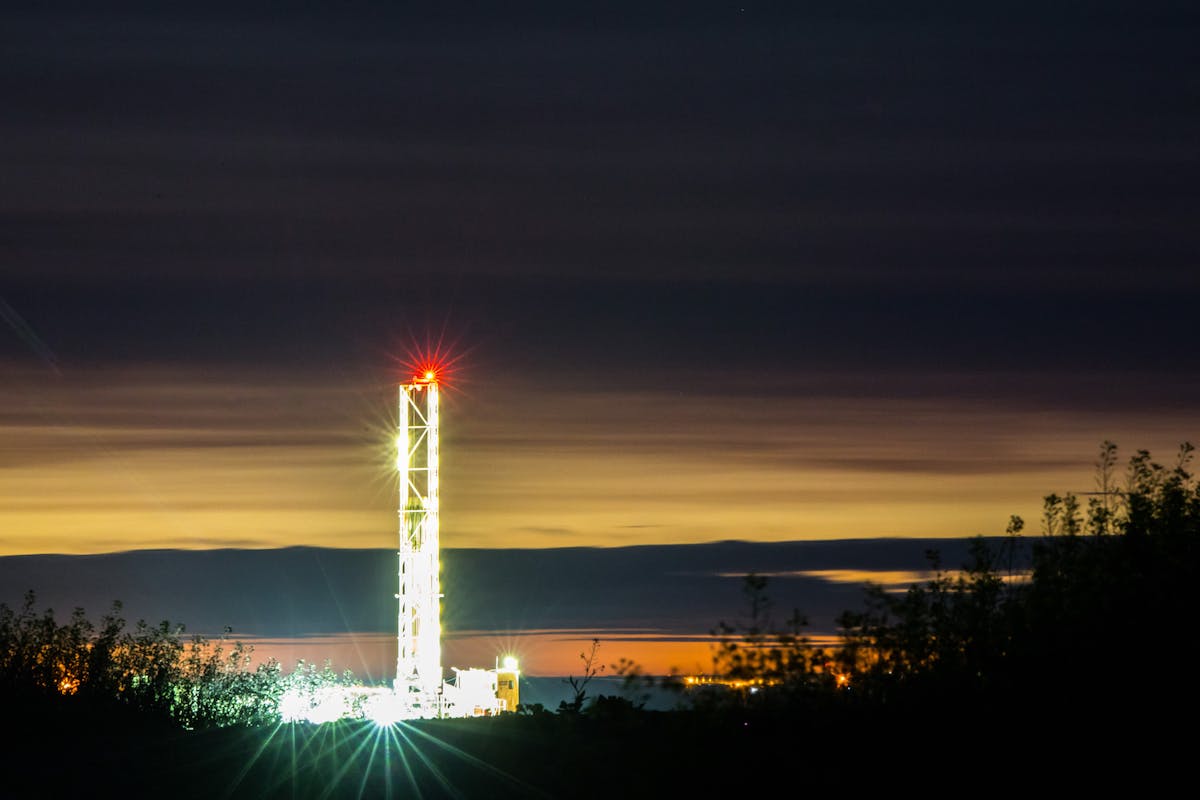 An oil rig at nighttime, lit with bright lights.
