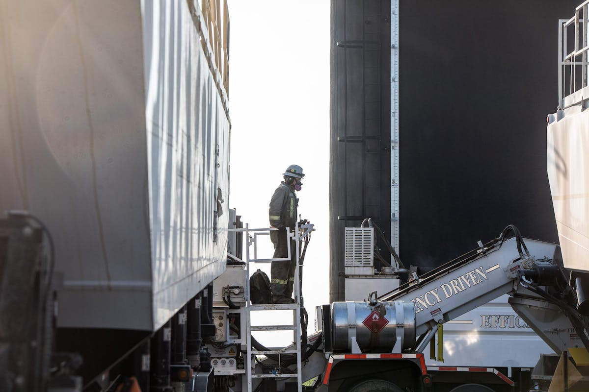 An oil worker wearing a mask, standing on a ladder.