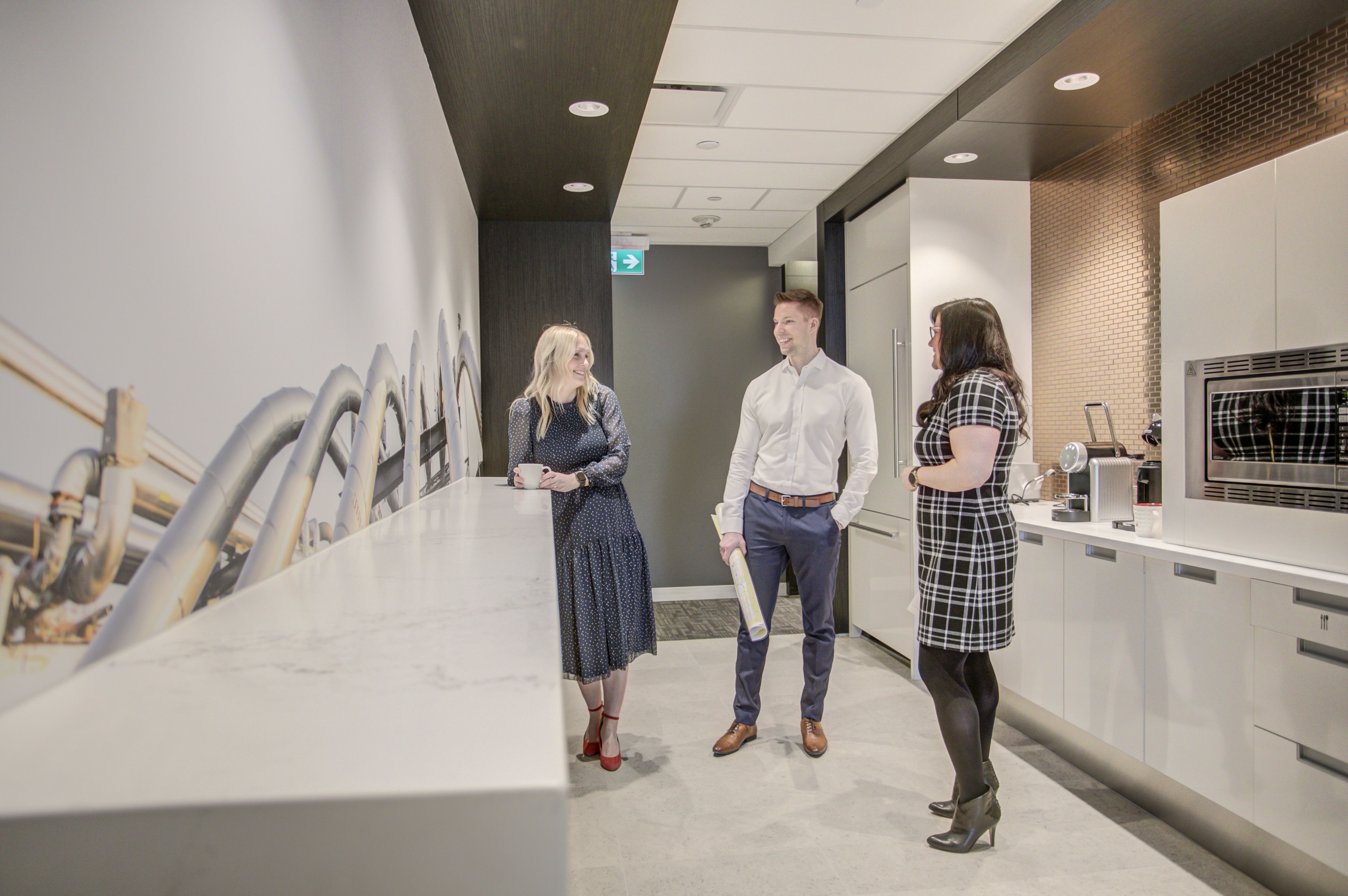 A group of people chat around coffee in an office kitchen