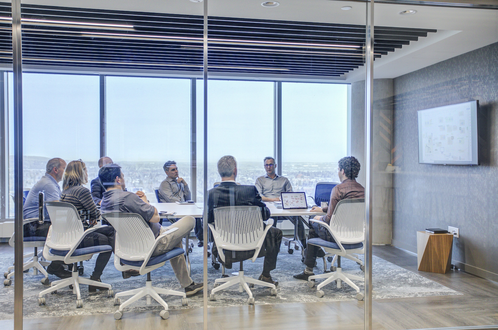 A group of office workers analyzing a screen during a presentation.