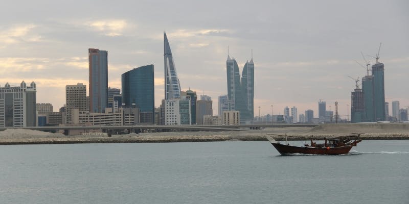 Traditional boat in the waters of Bahrain with modern skyscrapers in the background