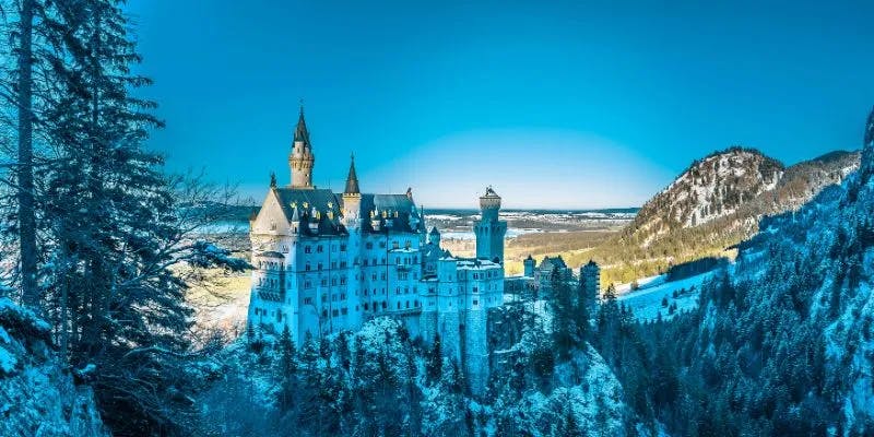 Winter view of Neuschwanstein Castle amidst snowy mountains.