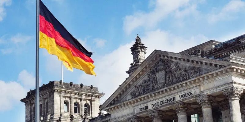 German flag waving above historic Reichstag building.