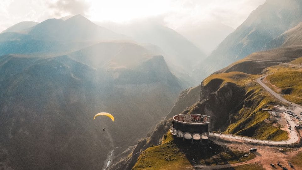 Paraglider soaring over scenic mountain landscape.