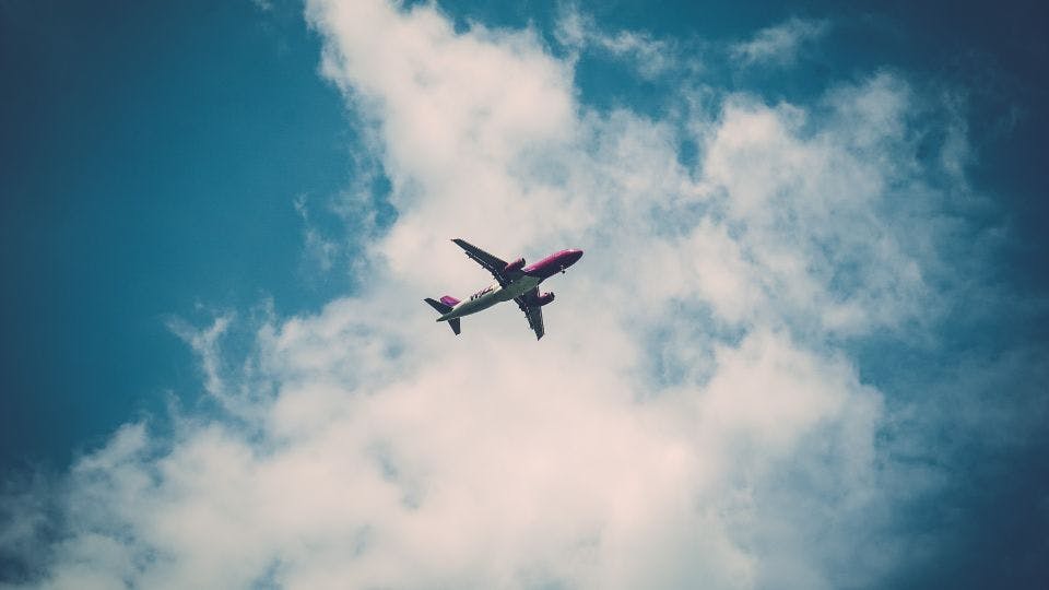 Airplane soaring in a partly cloudy sky.