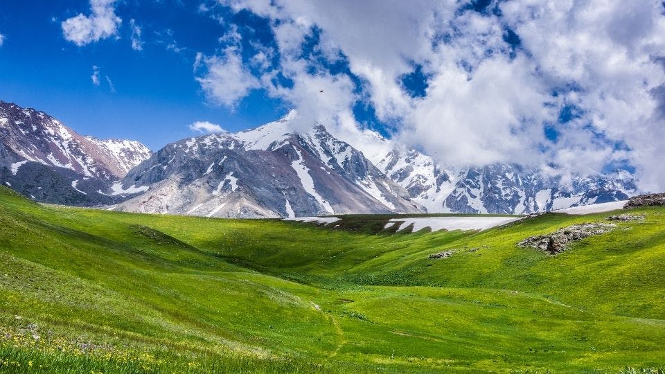 Snow-capped mountains with green valley.