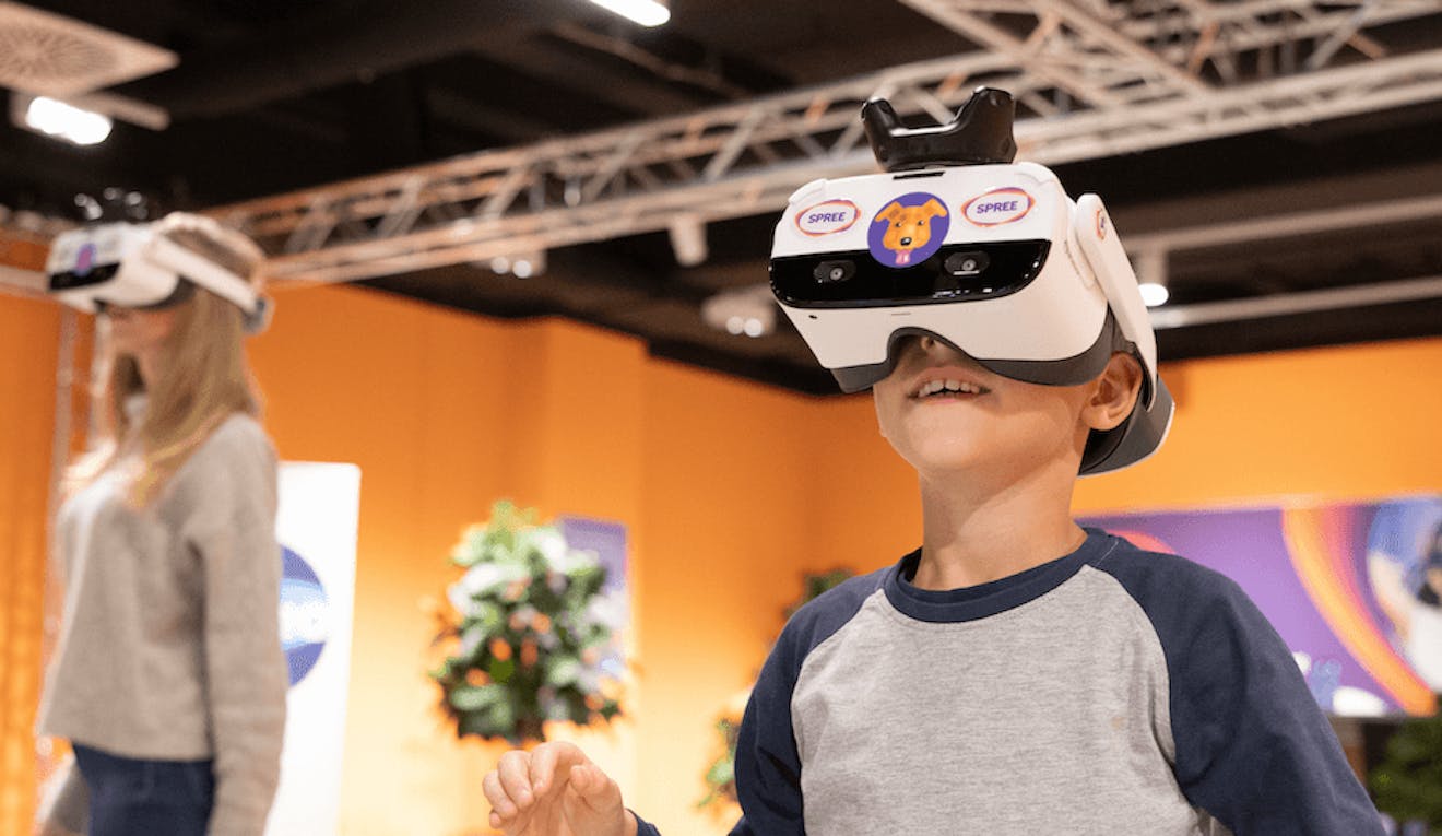 A young adult and child wear virtual reality headsets