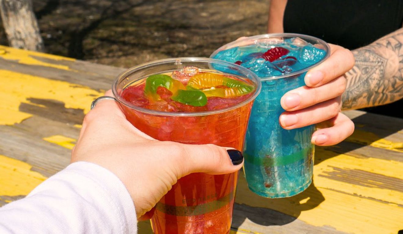 Two new summer drinks at TELUS Spark are cheers'd outside at a picnic table.