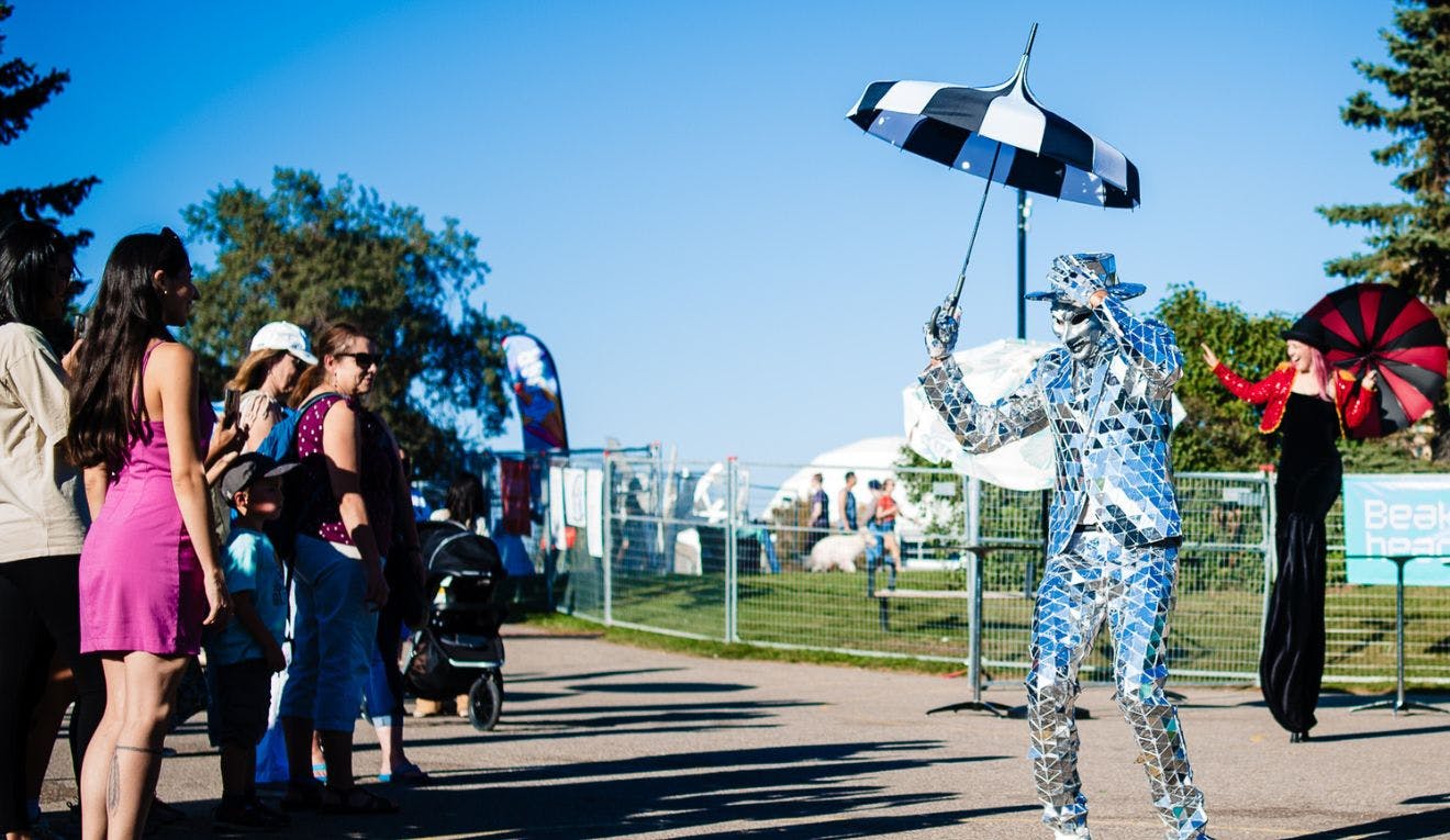 A man dressed in a disco ball mirror suit tips his hat to onlooking families at Beakerhead.