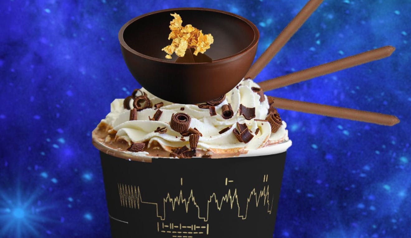 A fancy hot chocolate topped with whipped cream and chocolate shavings, in a cup decorated with scientific diagrams. The drink is against a blue galaxy background.