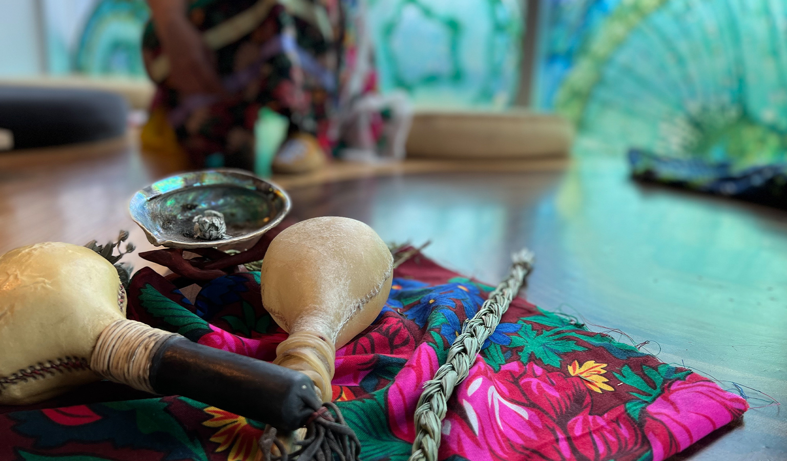 Indigenous rattles and braided sweet grass sit atop a ribbon skirt