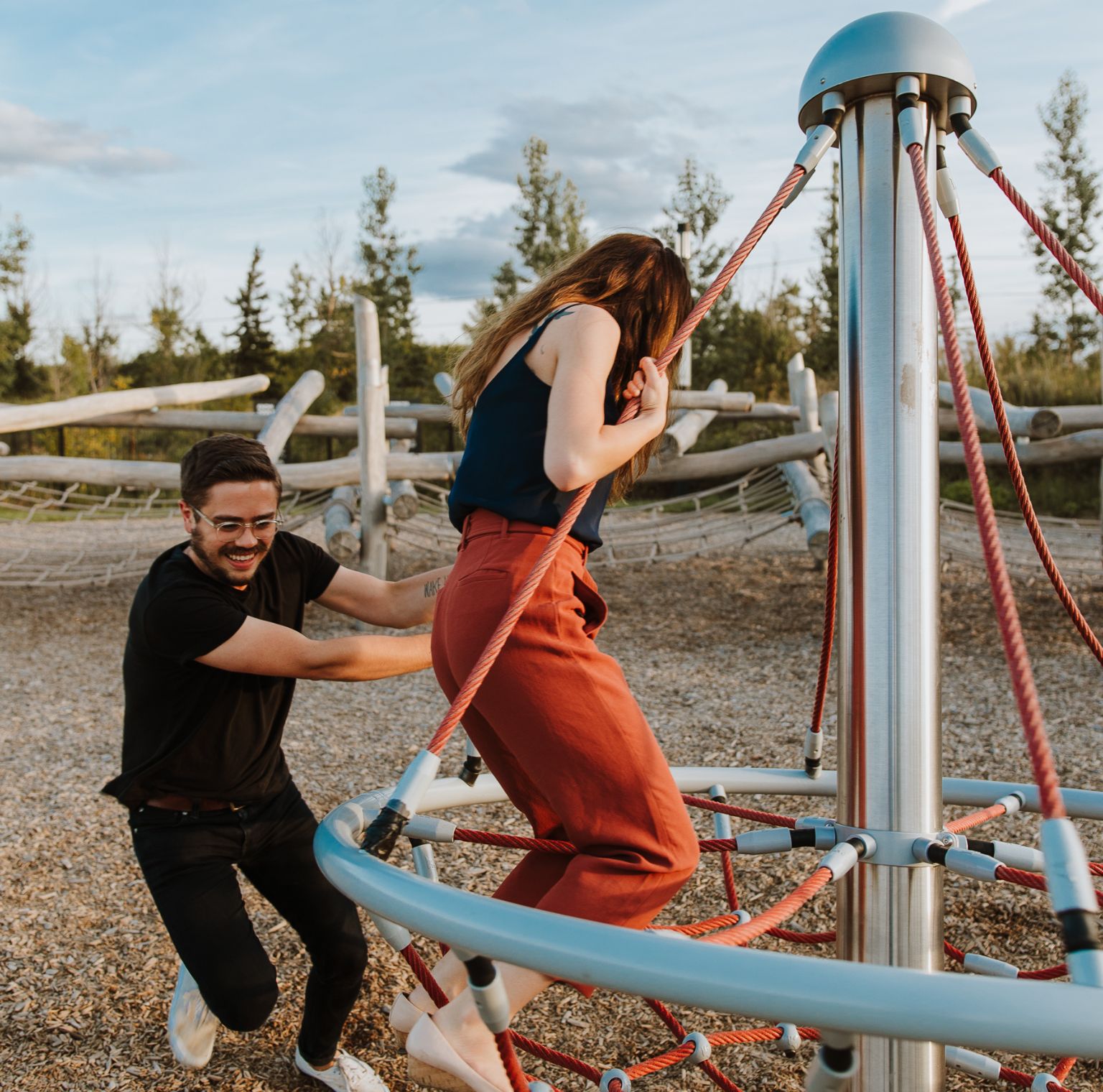 Two adults smile and have fun as they play in a playground