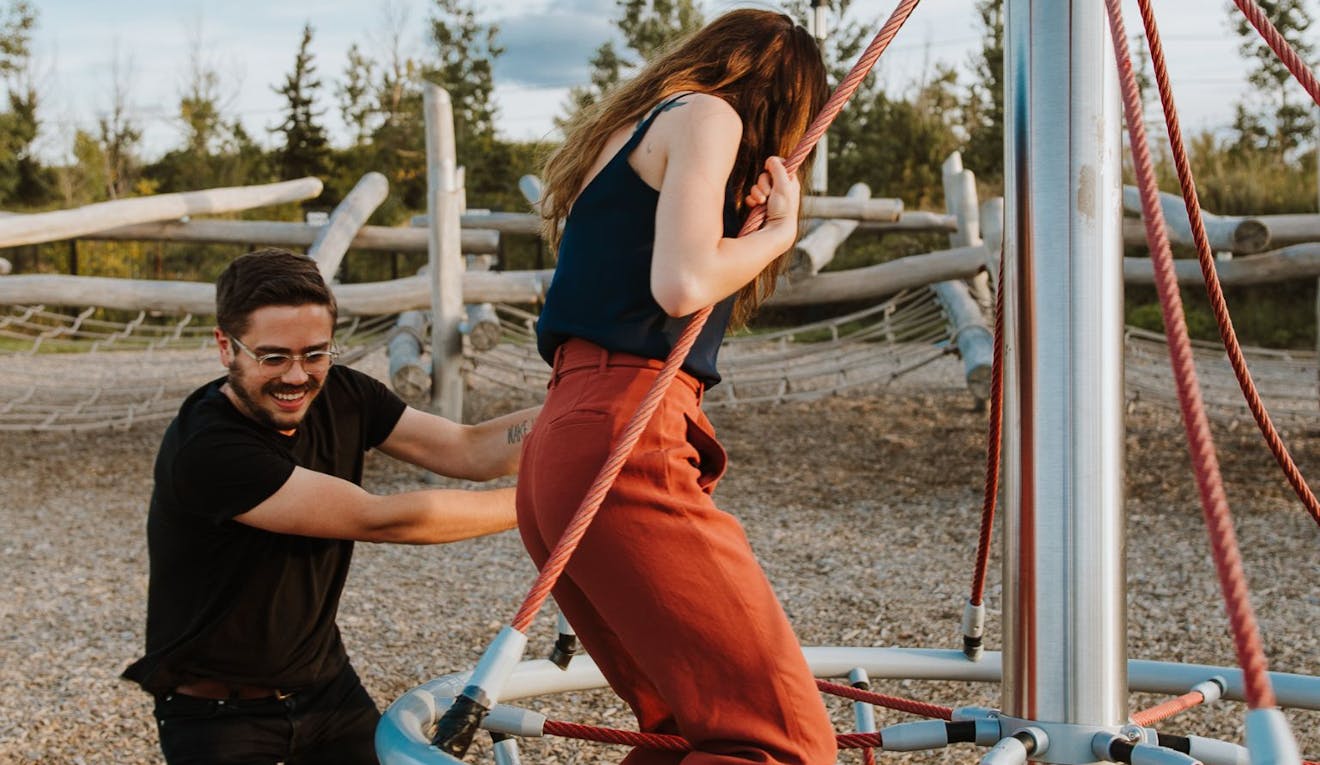 Two adults smile and have fun as they play in a playground