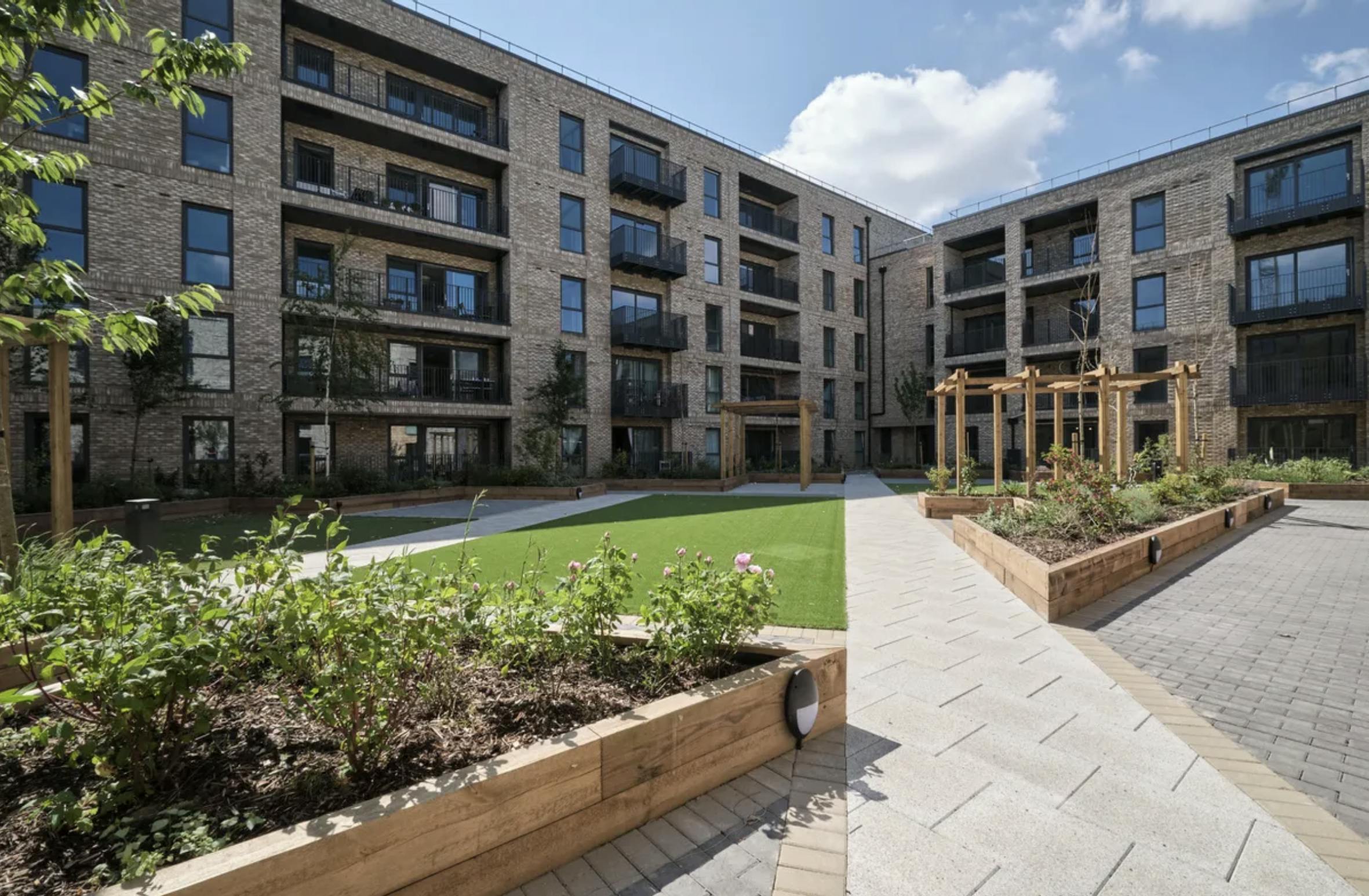 Block of flats in London with grass and planters in the foreground.