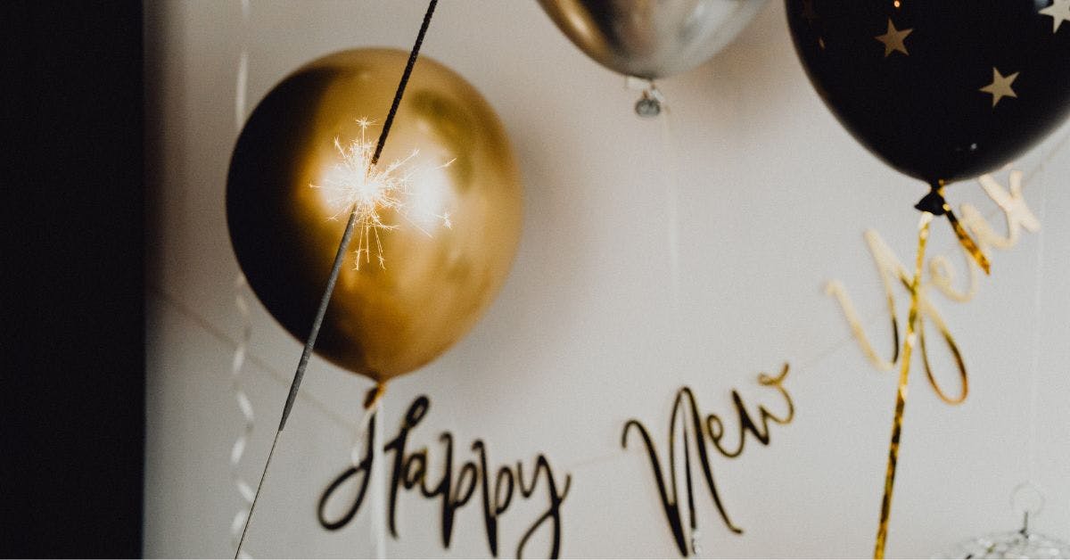 happy new year gold sign and matching balloons against white wall