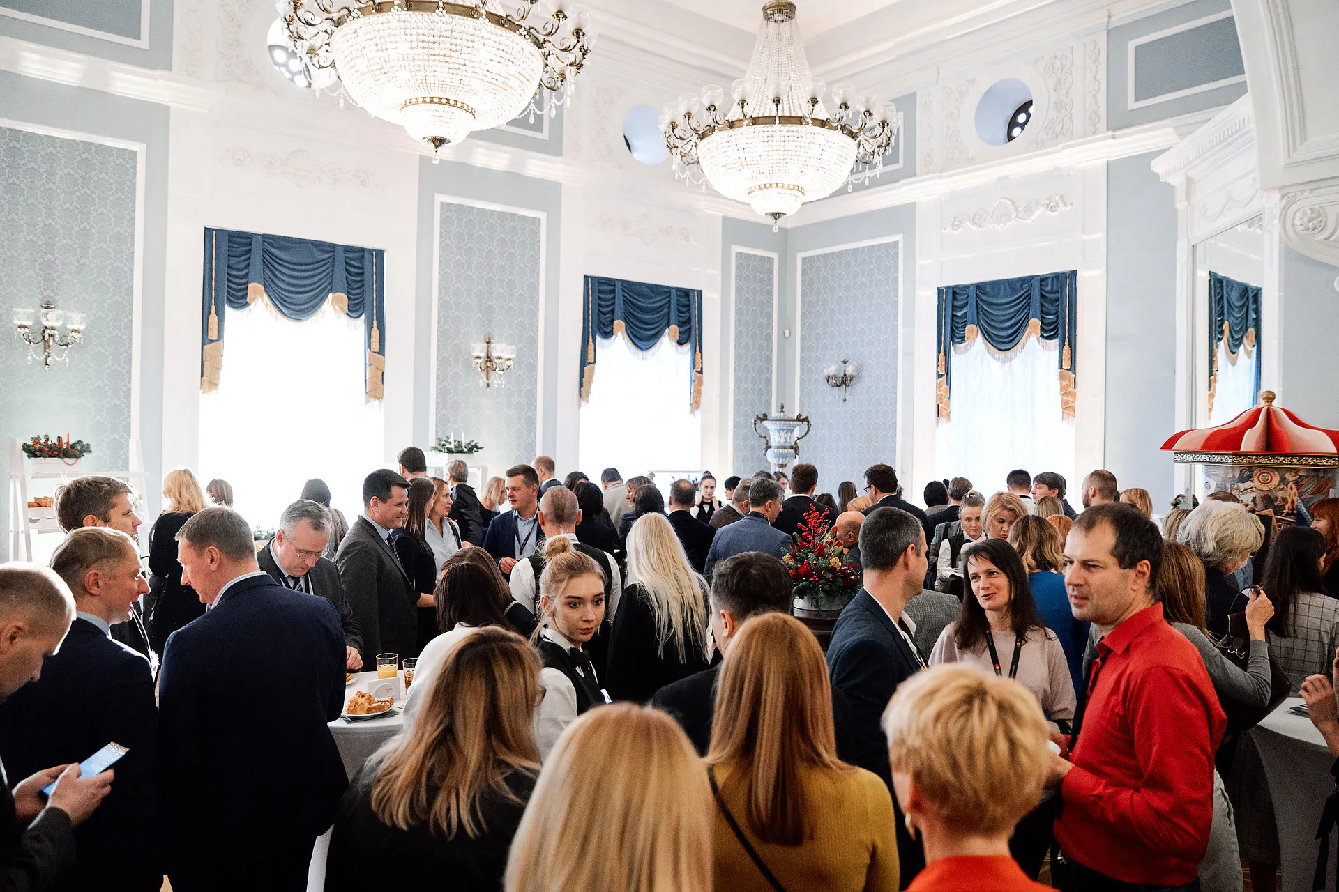 Masterday guests networking at a reception in a chandelier-lit hall