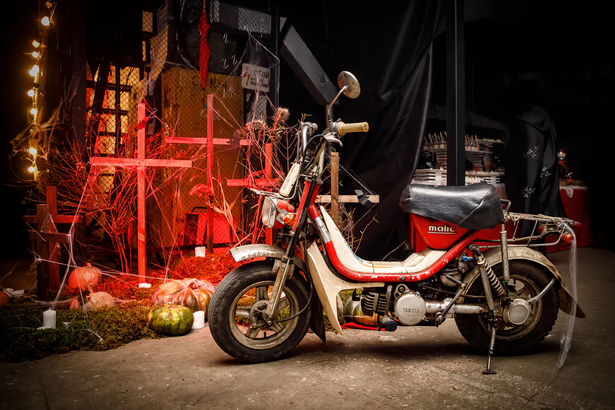 Vintage red moped among graveyard crosses, pumpkins, candles and cobwebs at the Wargaming Halloween party