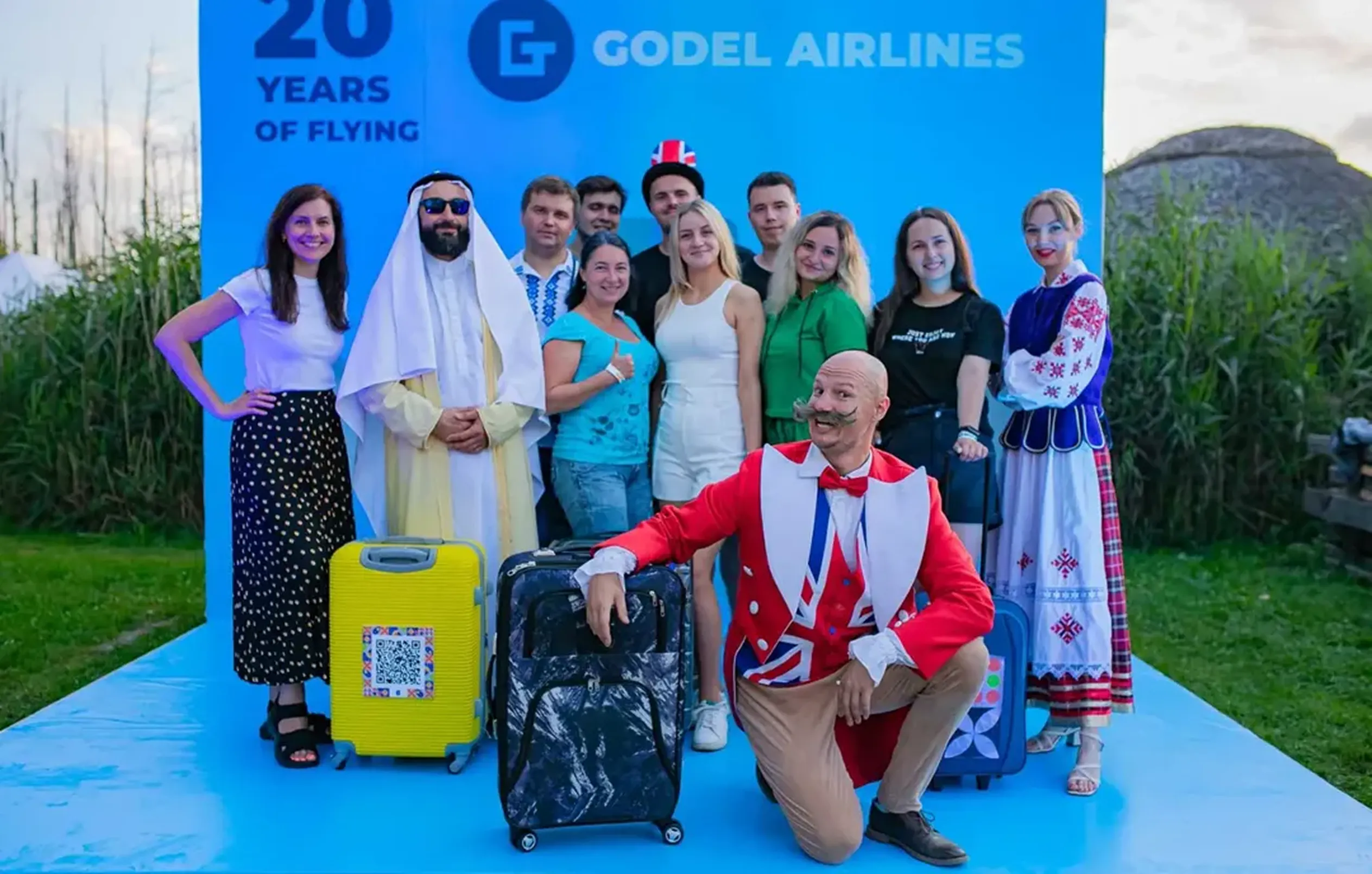 Godel team with costumed hosts and suitcases at the Godel Airlines 20 Years of Flying photo wall