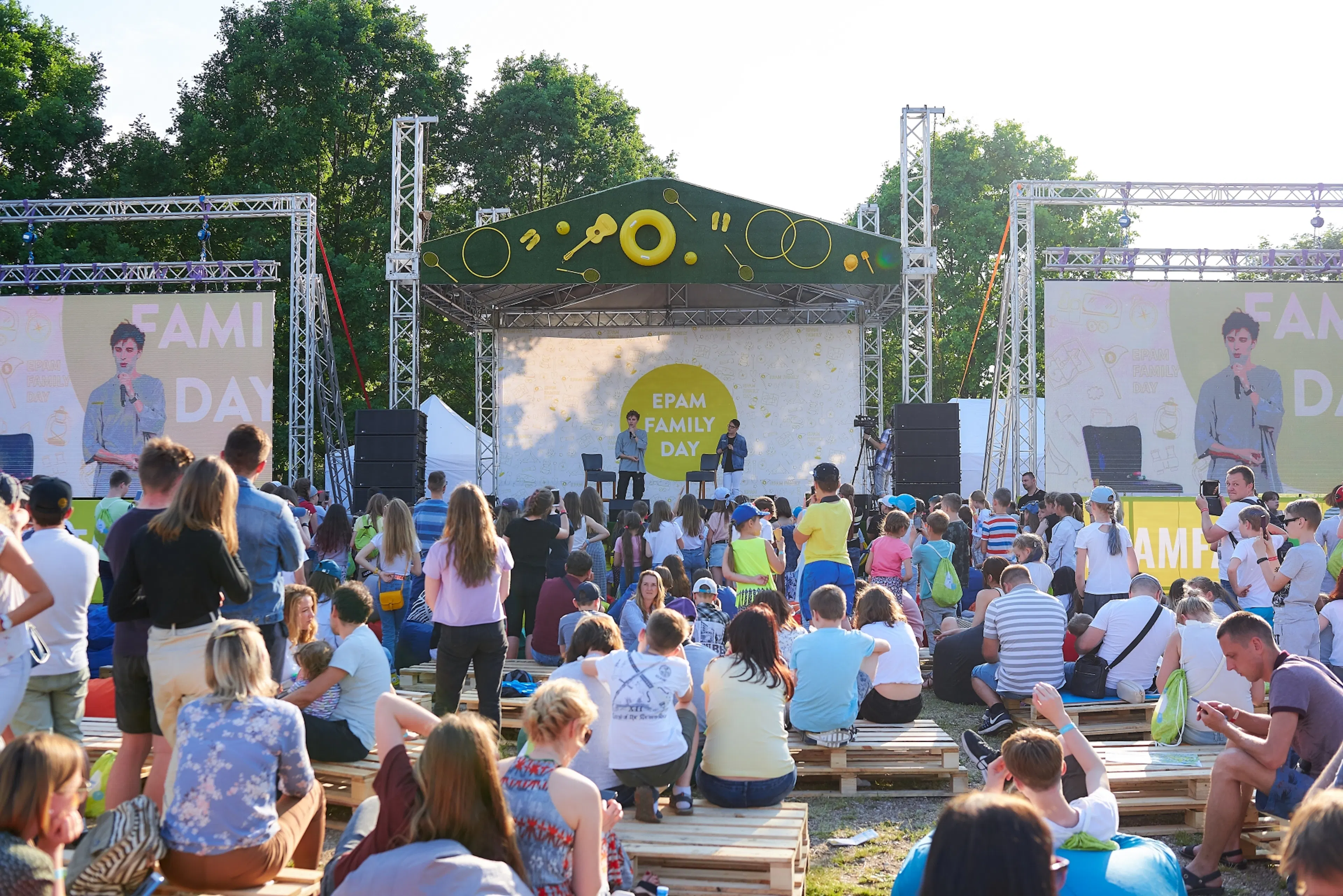 Główna scena EPAM Family Day z ekranami LED i rodzinami na siedziskach z palet w parku