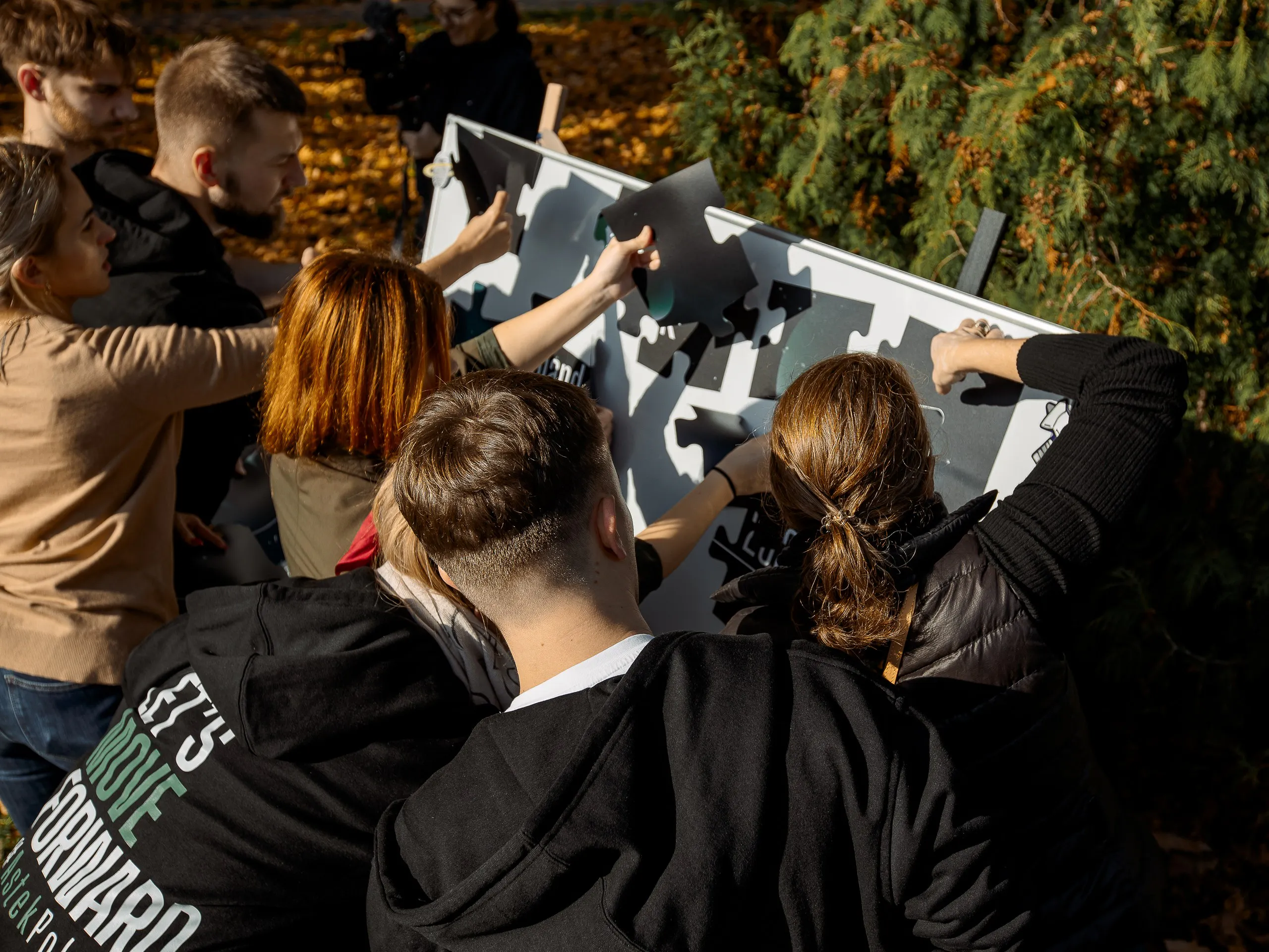 Astek Polska team assembling a giant puzzle board outdoors during a team-building activity