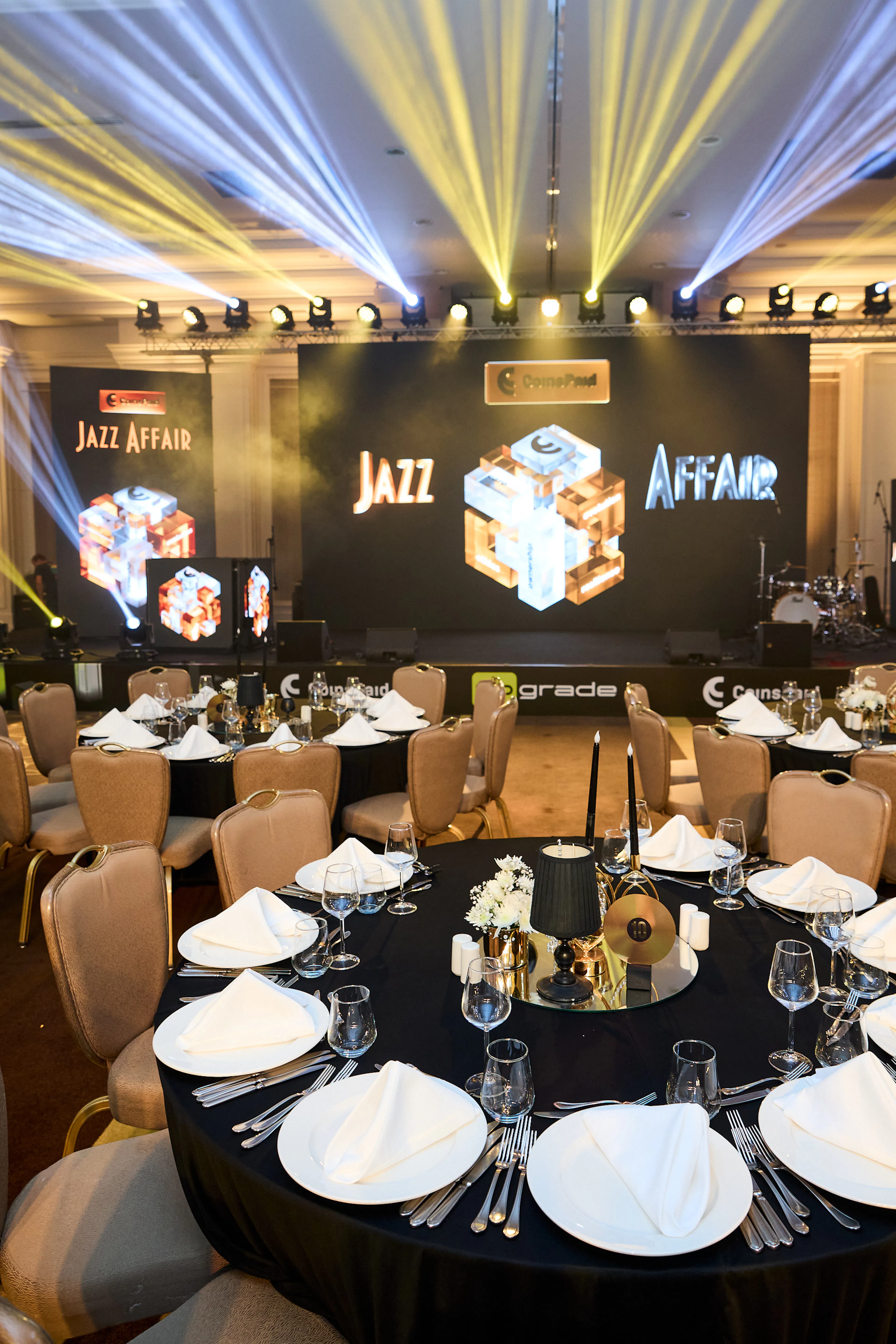 Sala gali CoinsPaid Jazz Affair z nakrytymi stołami, sceną LED i efektami świetlnymi