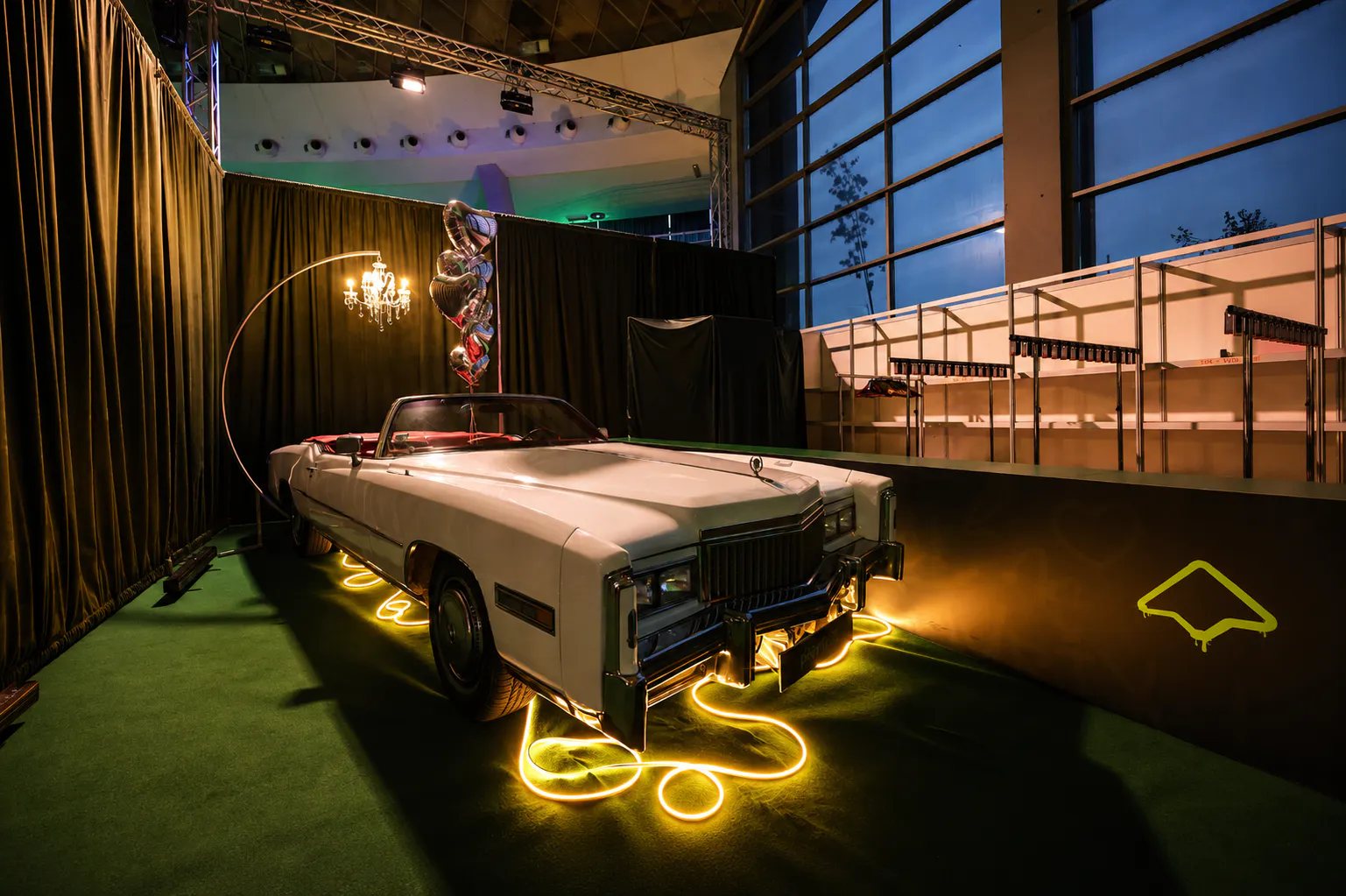 Vintage white American convertible framed by neon rope light and a chandelier in the Playrix photo zone