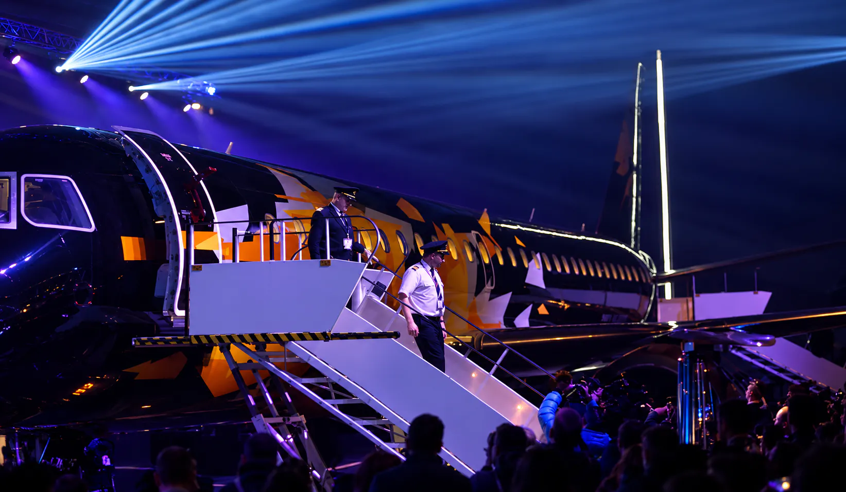 Pilots descending the stairs of the Tankolet 2.0 aircraft in front of press photographers