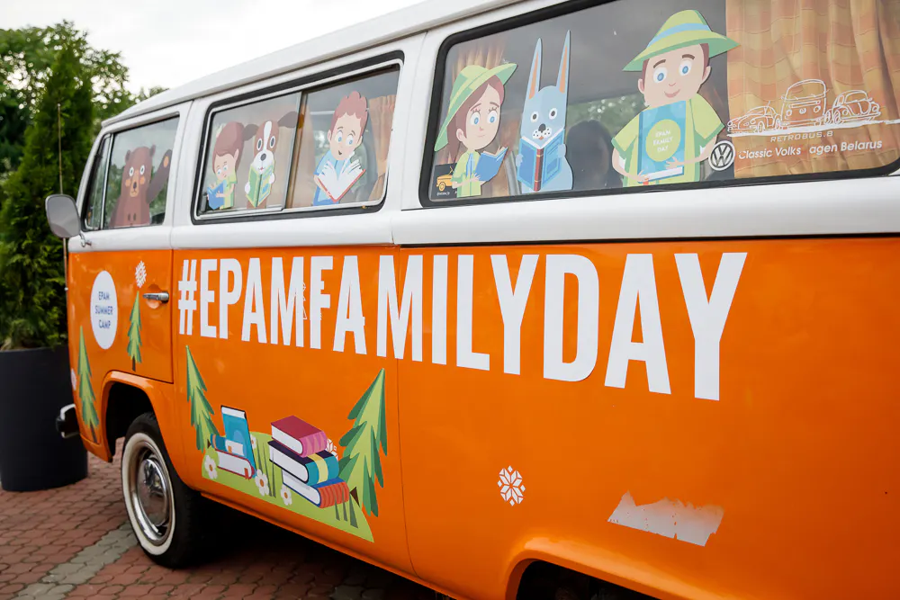 Orange vintage VW bus branded #EPAMFAMILYDAY with cartoon characters in the windows
