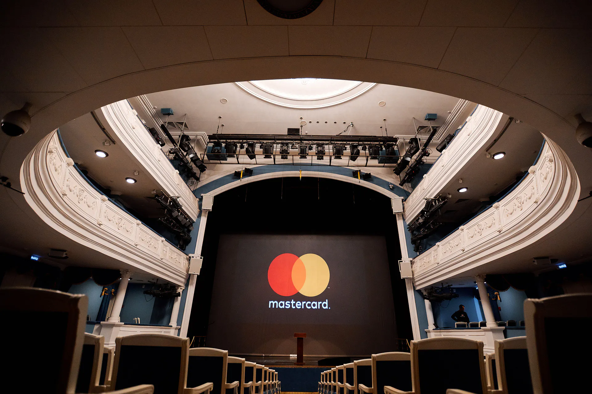 Mastercard logo on the stage screen framed by the theatre's ornate balconies and lighting rigs at Masterday