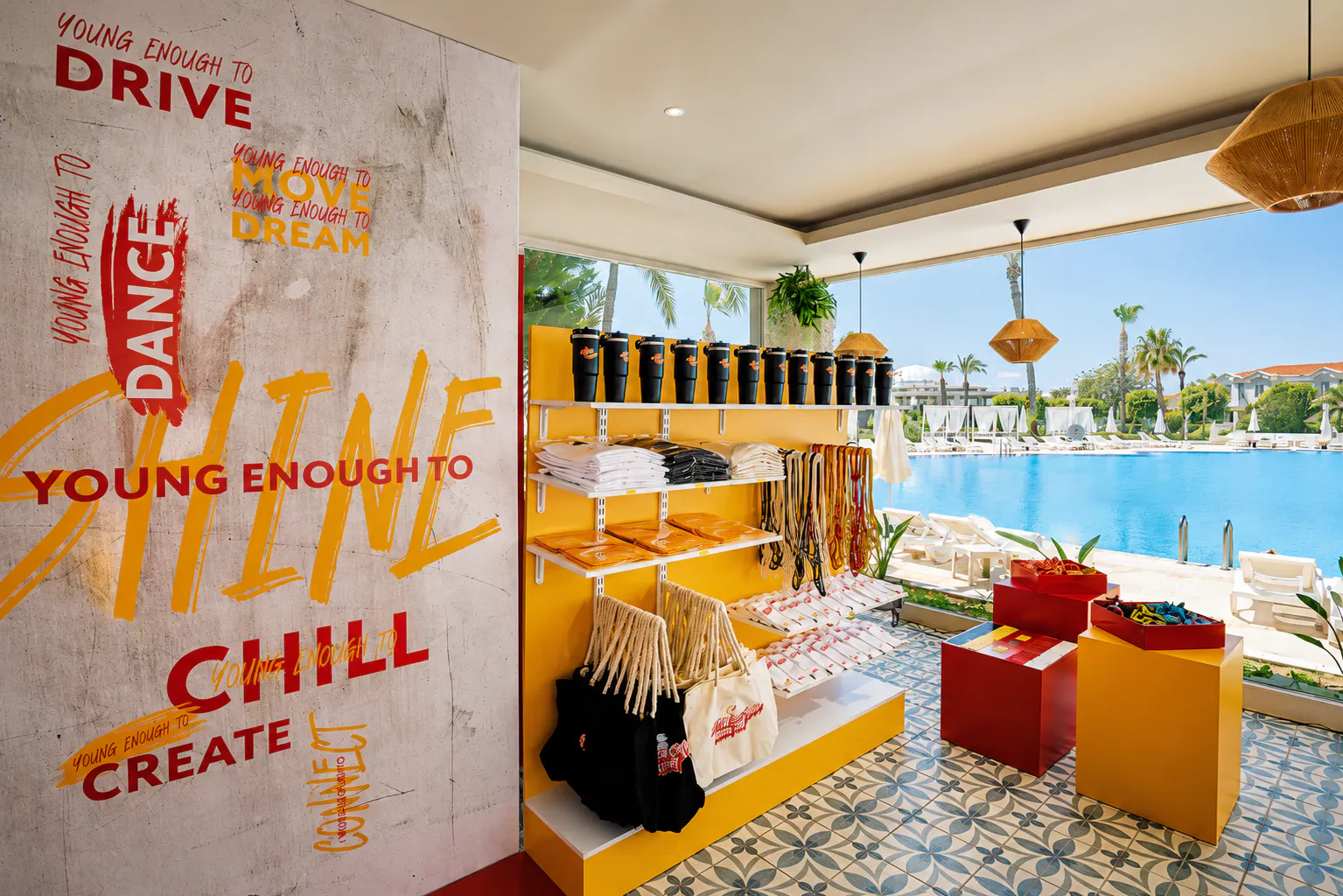Young Fest merch corner with branded tumblers, T-shirts and tote bags next to the resort pool