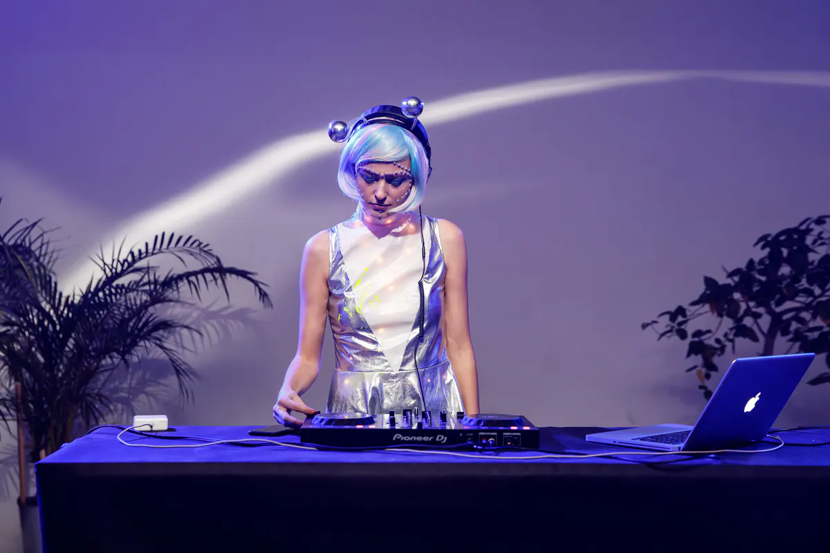 DJ in a silver space-themed costume and wig playing a set at the Wargaming Halloween party