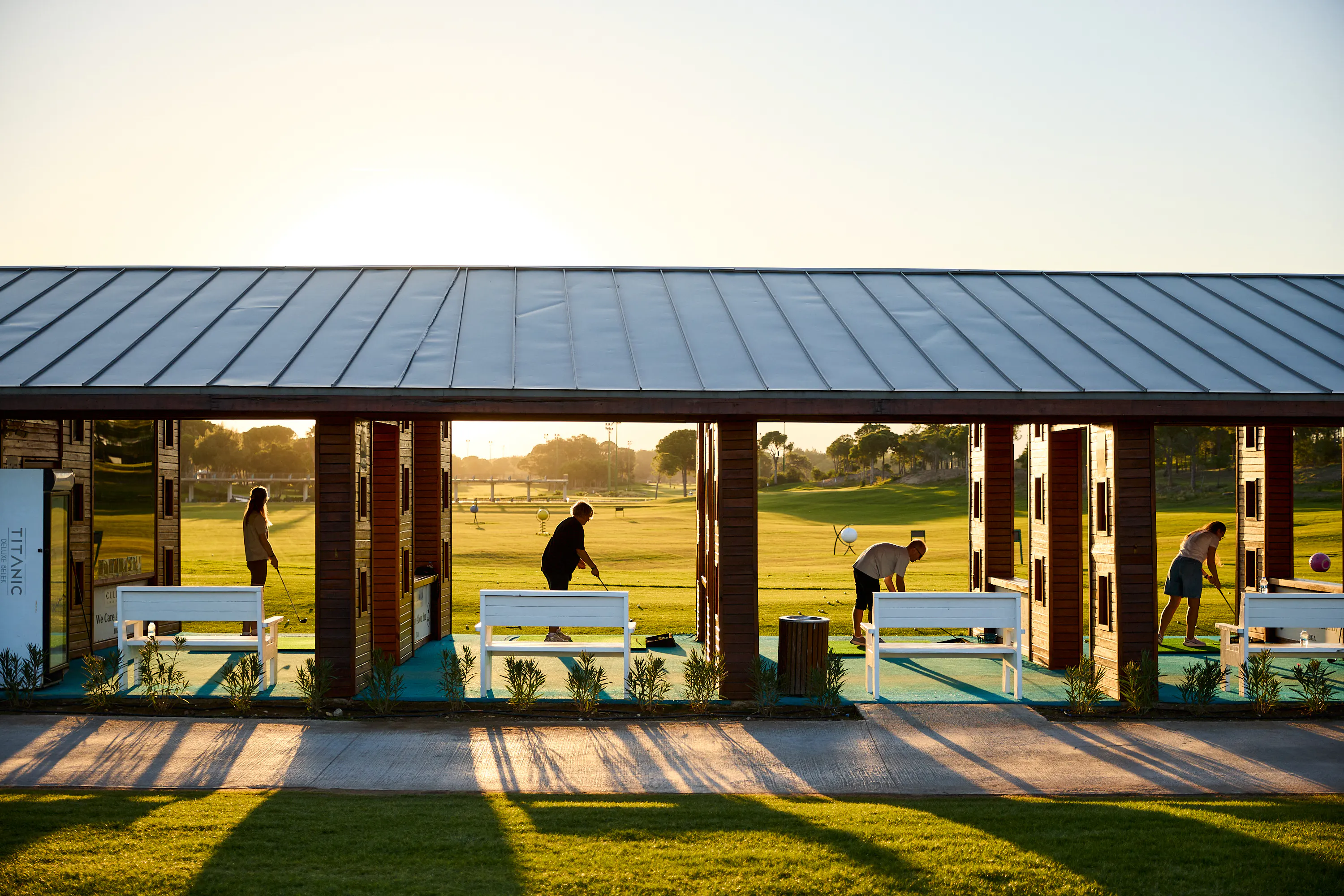 Guests practising at a golf driving range at sunset during the CoinsPaid event in Turkey