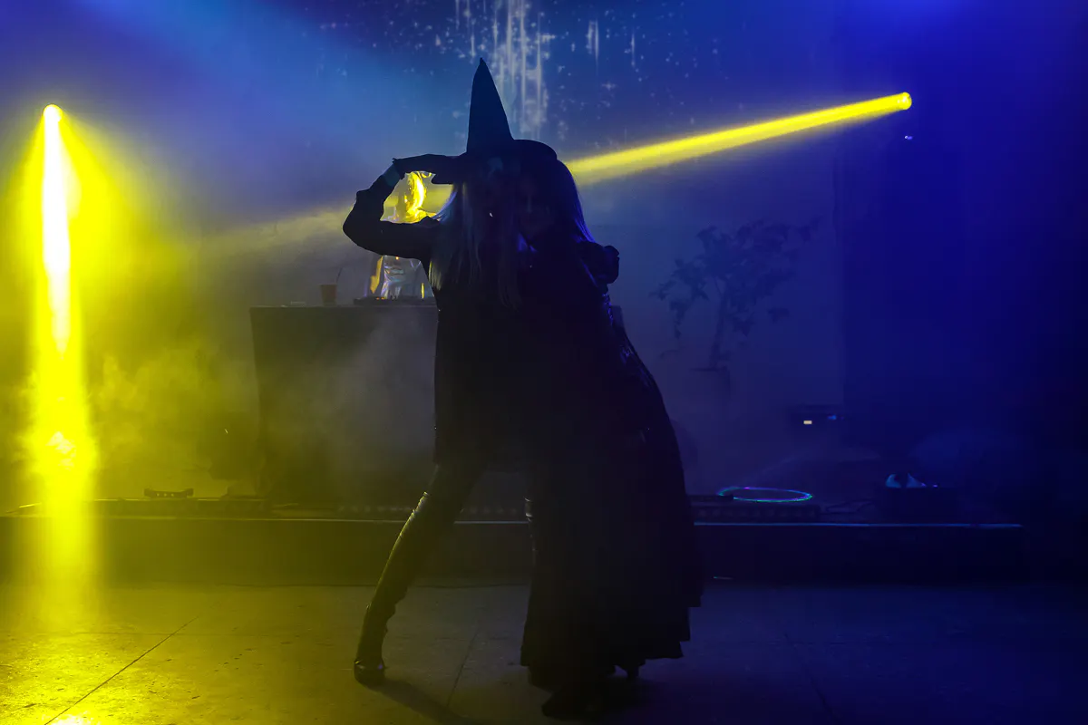 Two guests in witch costumes posing in yellow spotlight beams on the dance floor
