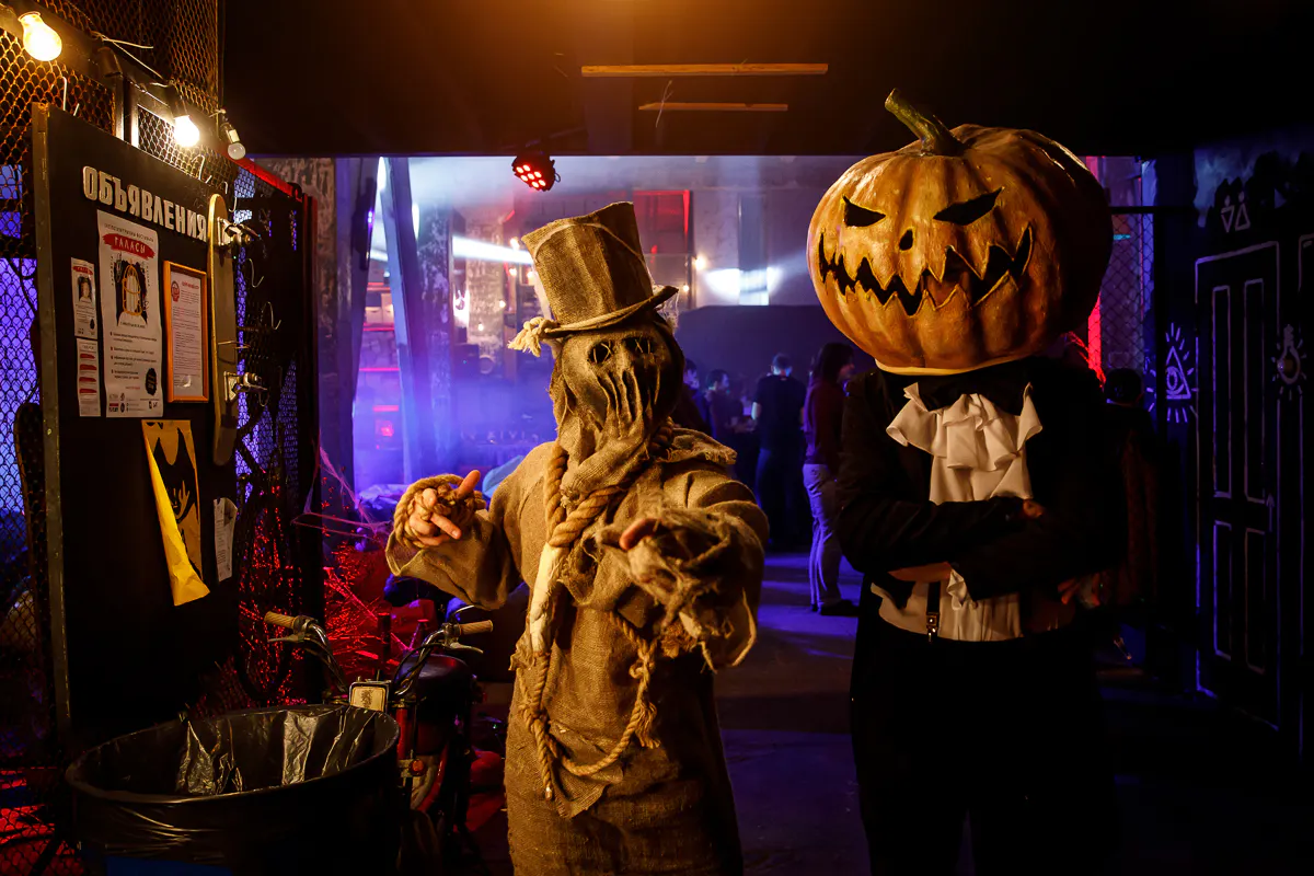 Postacie stracha na wróble i dyniogłowego ze spektaklu immersyjnego Wargaming Halloween w industrialnym wnętrzu