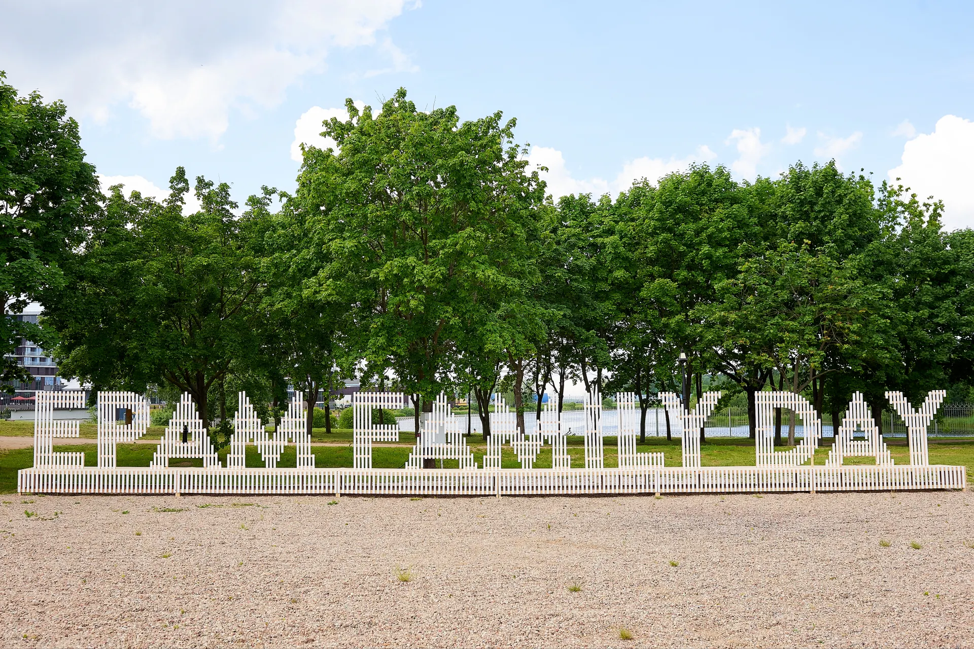 Giant white slatted EPAM FAMILY DAY letters installed on a lawn in front of a row of trees