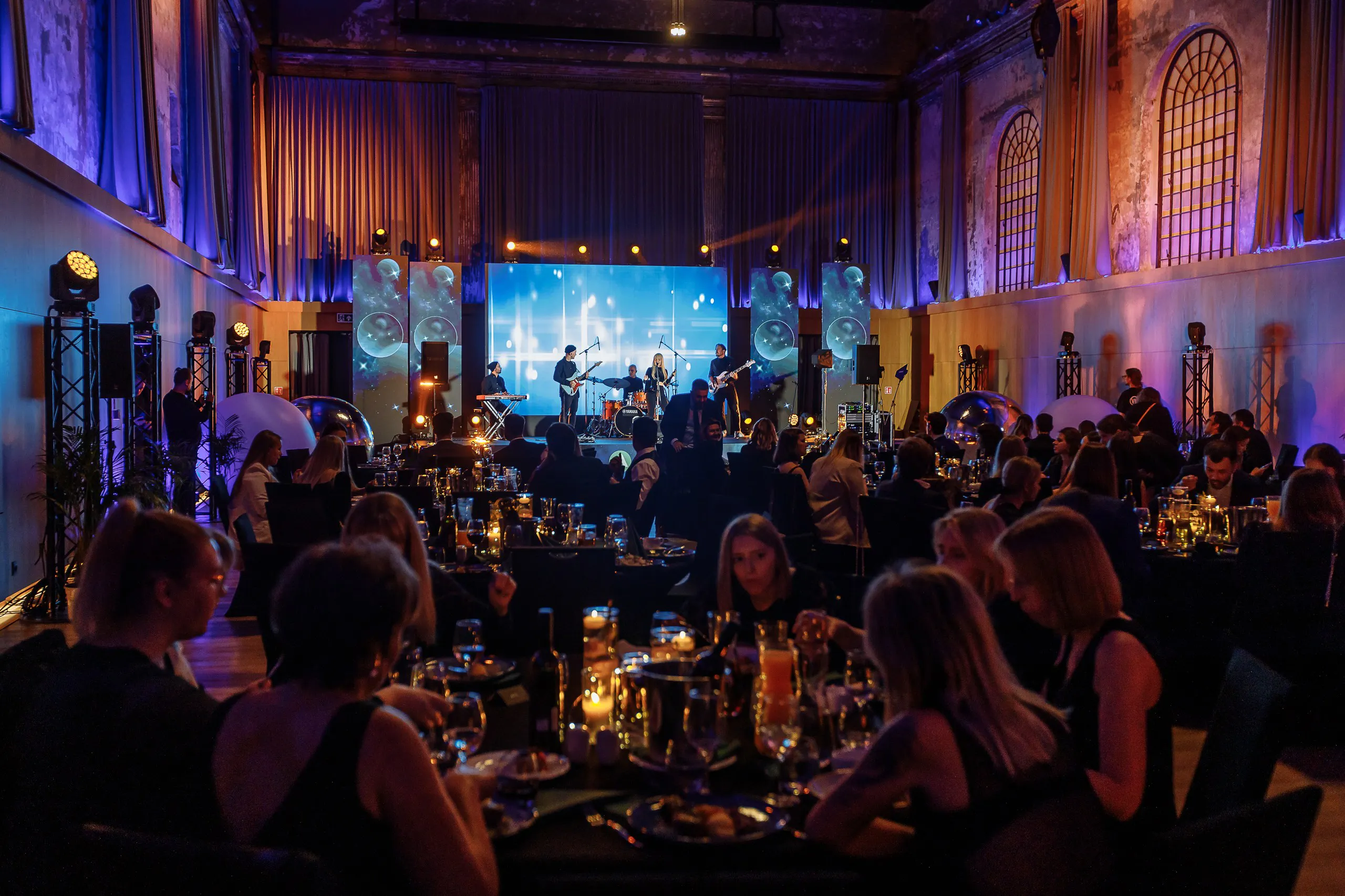 Live band performing on stage while guests dine at candlelit tables during the Astek Constellation gala