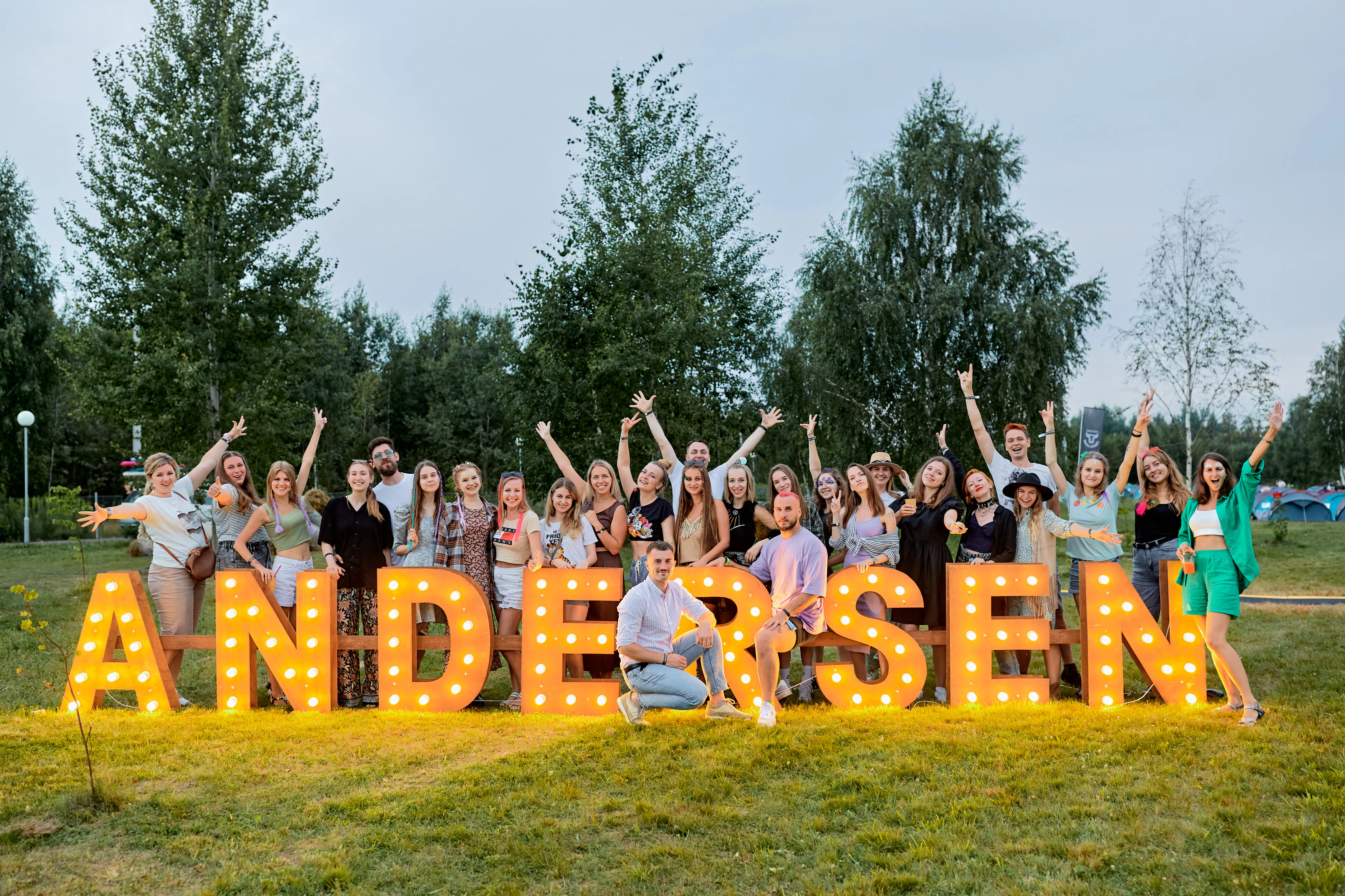 Andersen employees cheering behind giant illuminated ANDERSEN marquee letters on the festival lawn