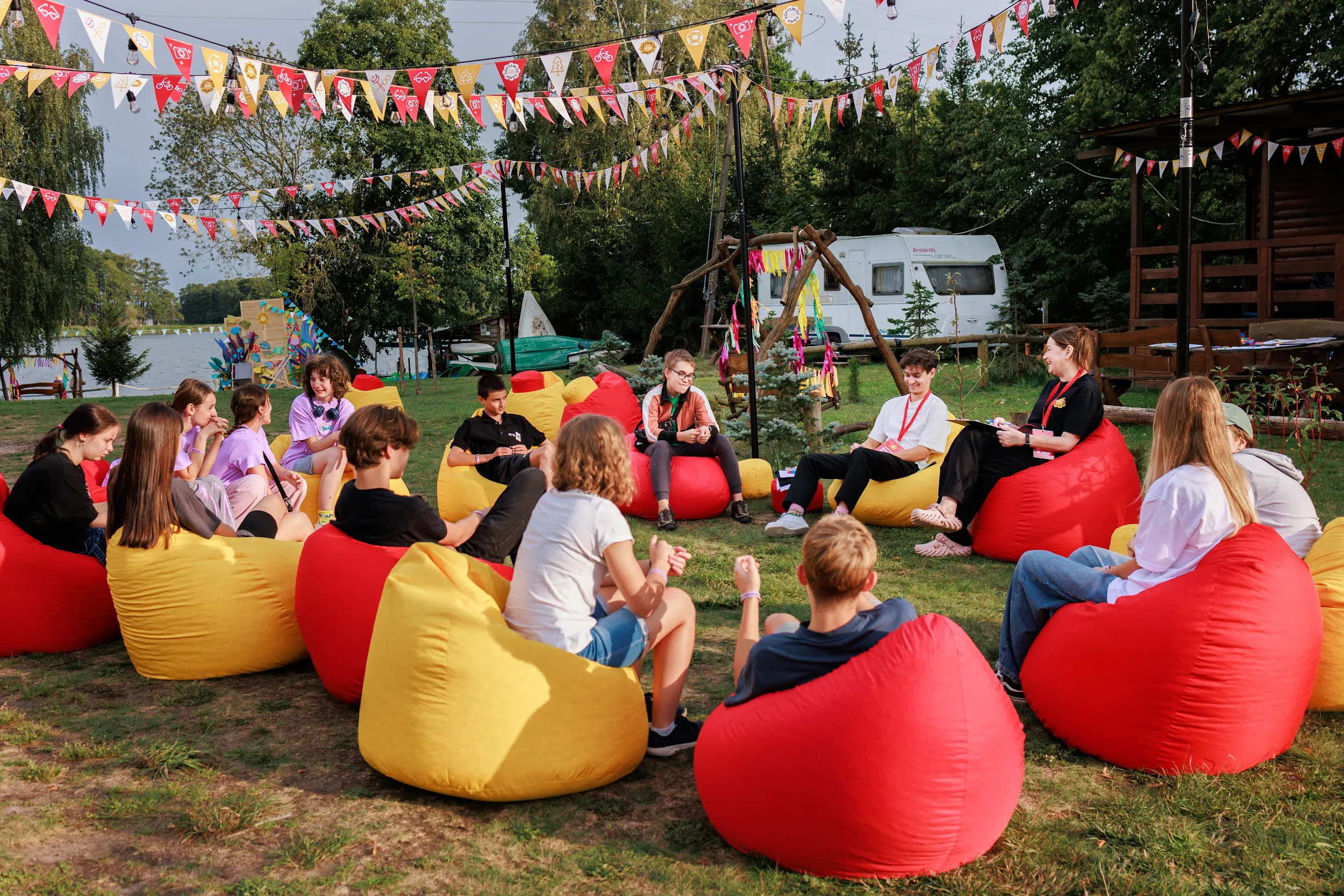 Children and counsellors sitting in a circle of red and yellow bean bags at the lakeside camp