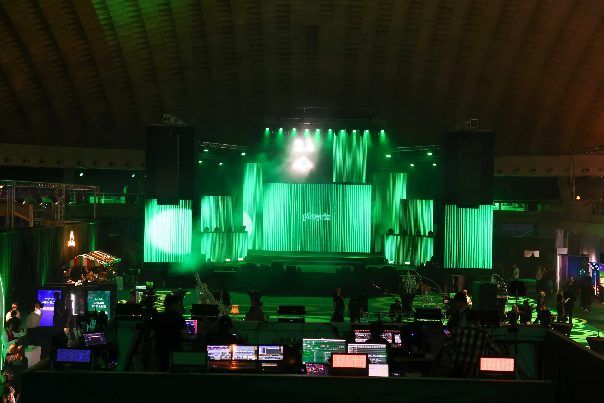 Green-lit Playrix stage with LED columns seen from the sound and lighting control desk