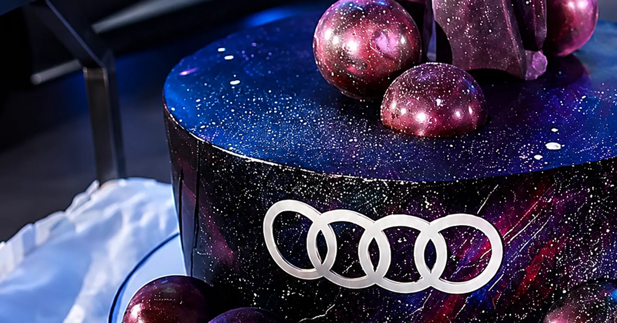 Galaxy-glazed cake with the Audi rings logo and glossy chocolate spheres