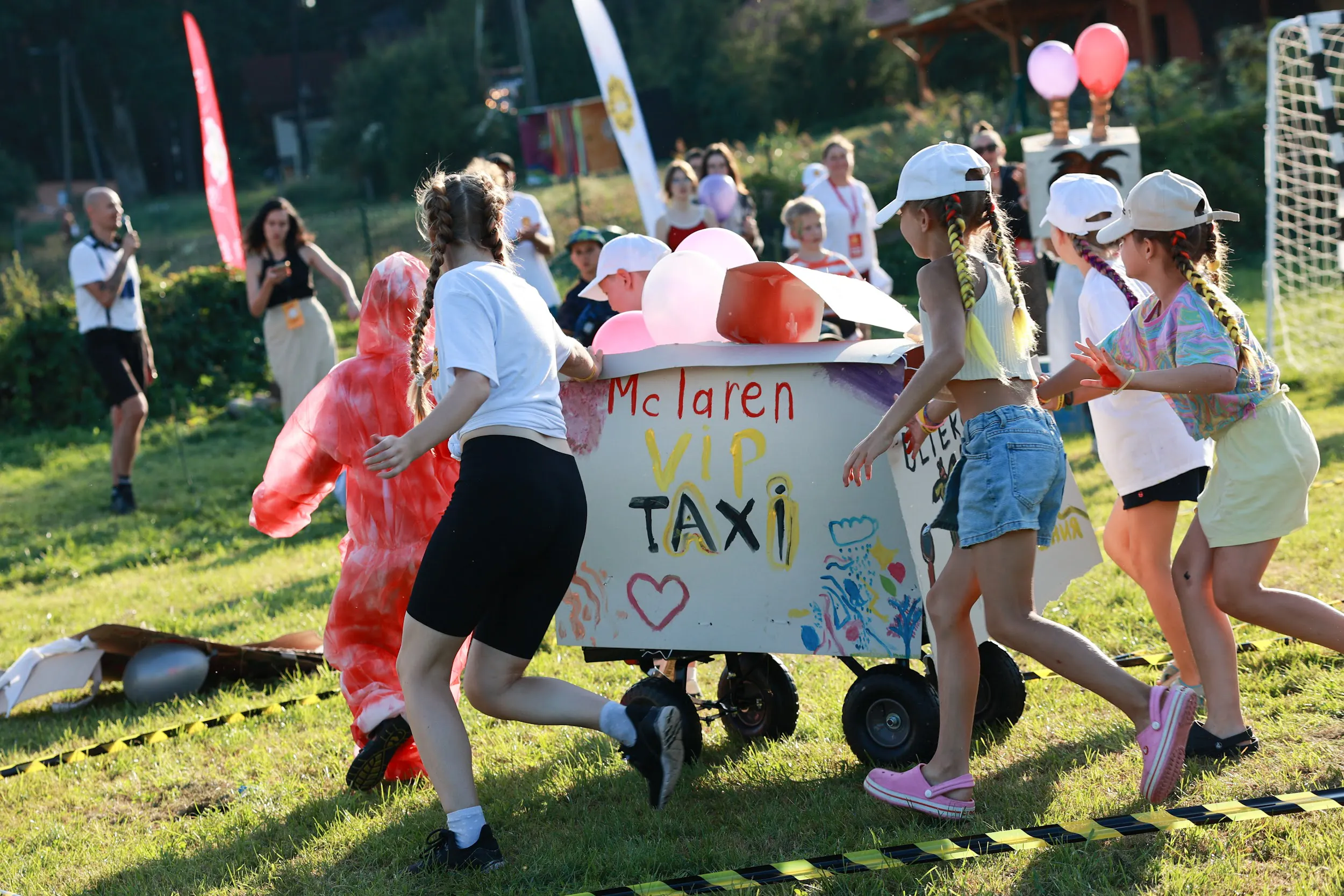Children racing a handmade VIP Taxi cart during team competitions at SOFTSWISS Kids Camp