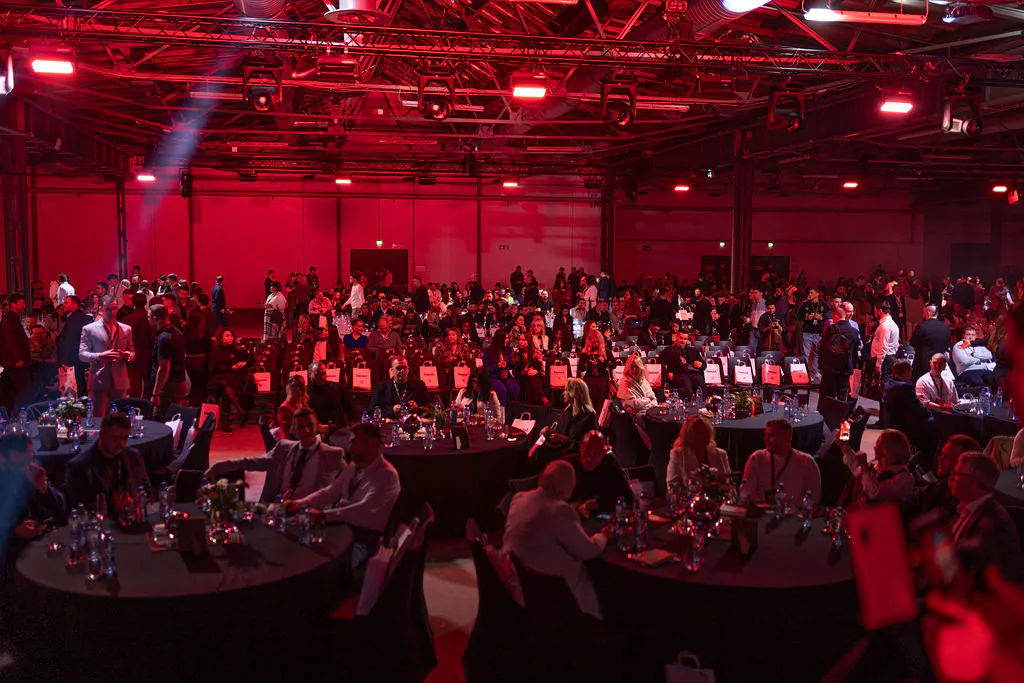 Guests at round tables and theatre seating in the red-lit Station Berlin hall at Boost Forum Berlin