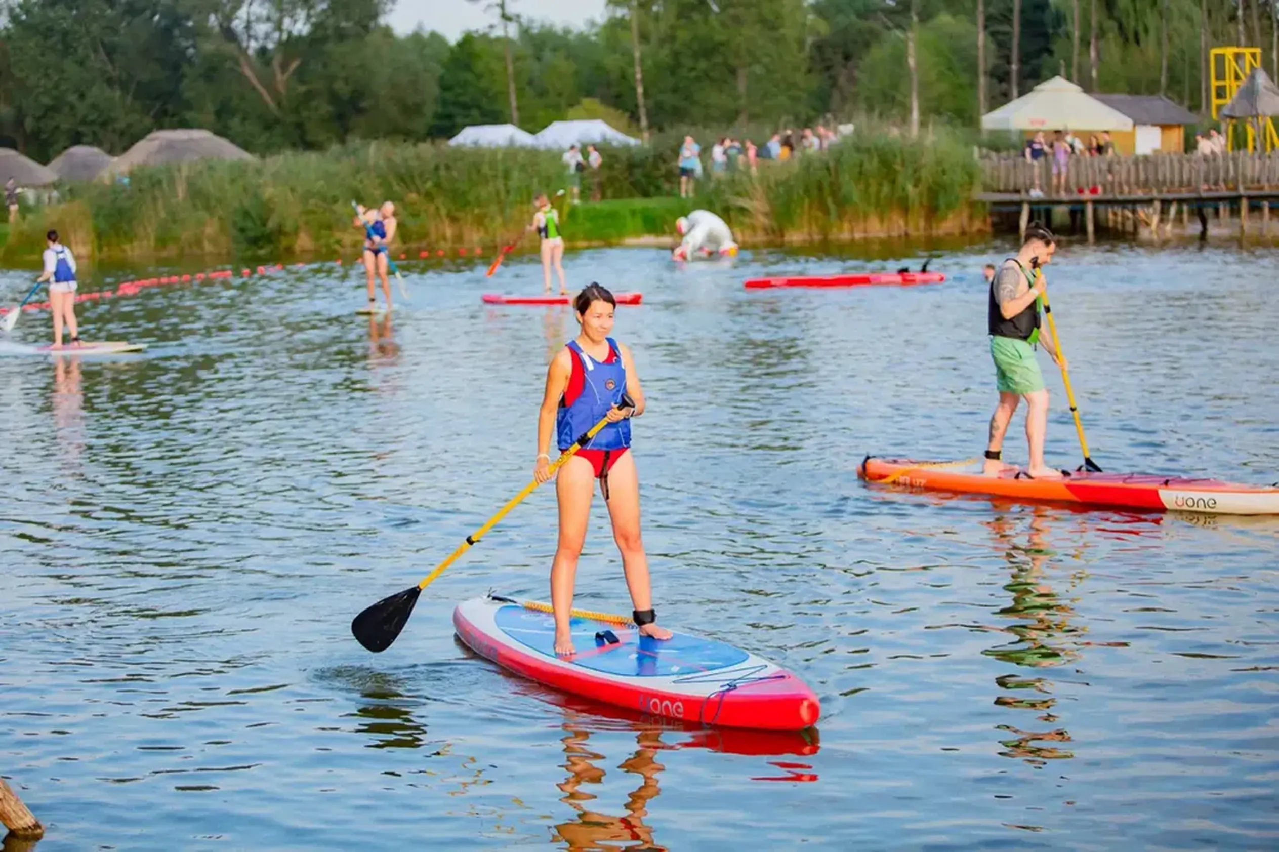 Godel employees stand-up paddleboarding on the lake during the summer team-building event