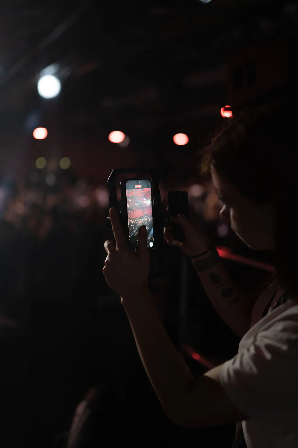 Attendee filming the stage on a smartphone rig in the darkened conference hall at Boost Forum Berlin