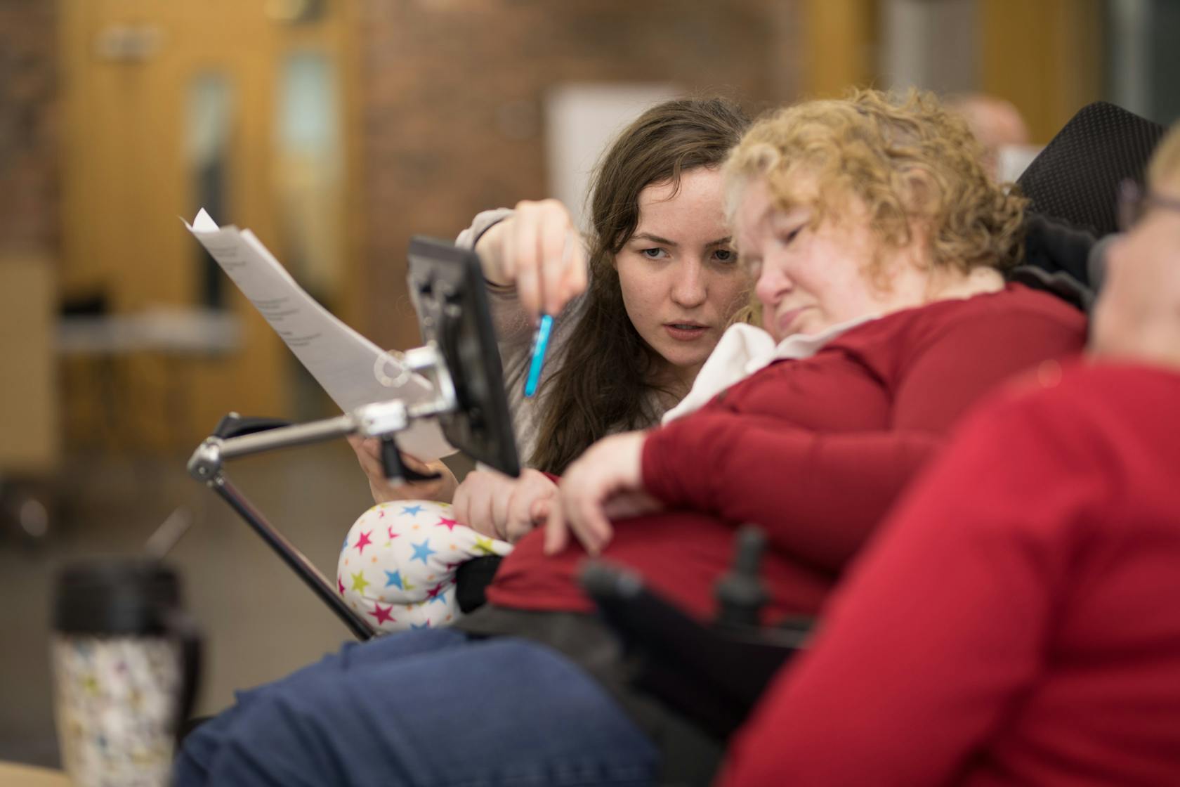 Two women looking  at an assistive screen.