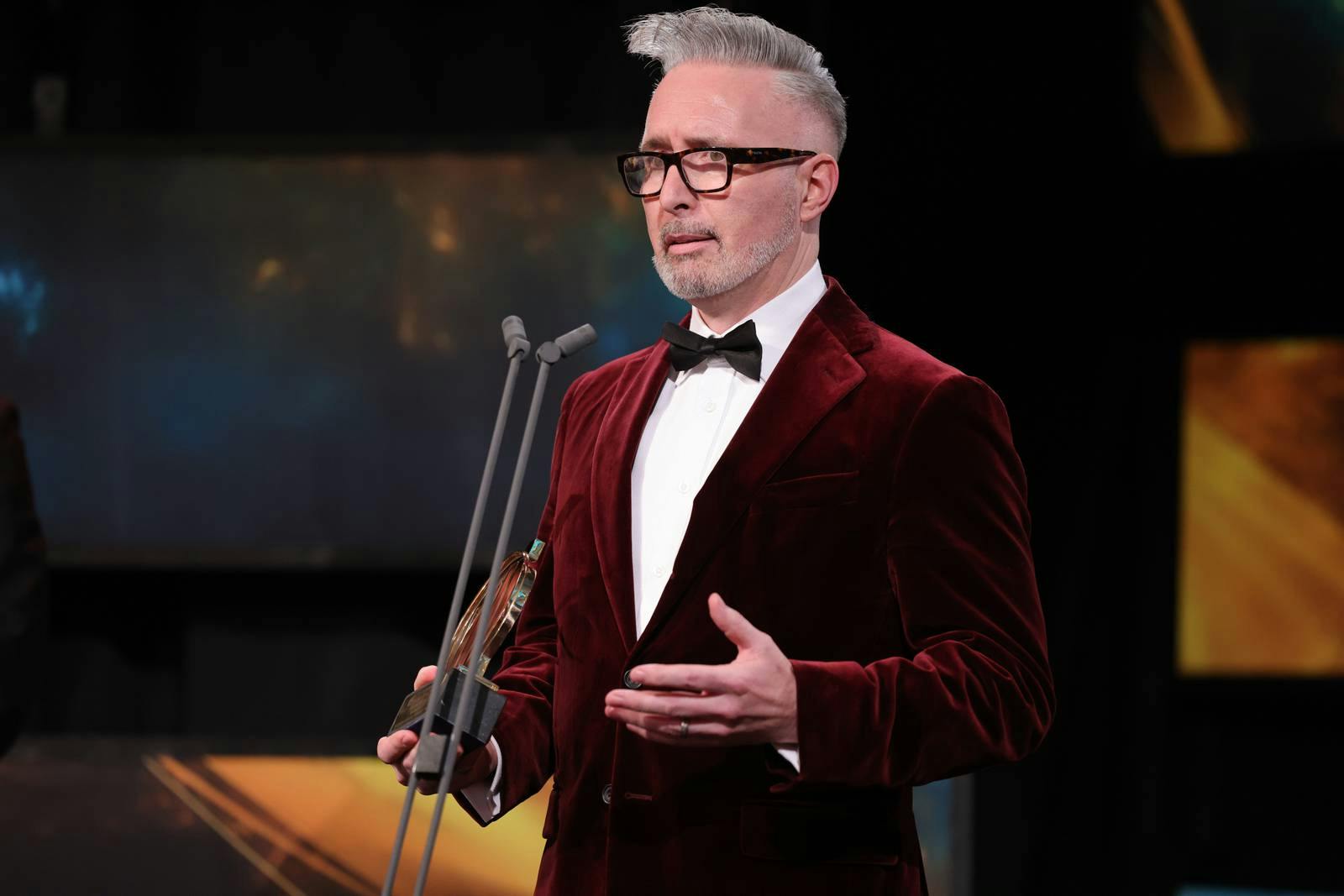Martin McKay wearing a read velvet suit on stage at the EY Entrepreneur of the Year awards in Powerscourt, giving his acceptance speech 