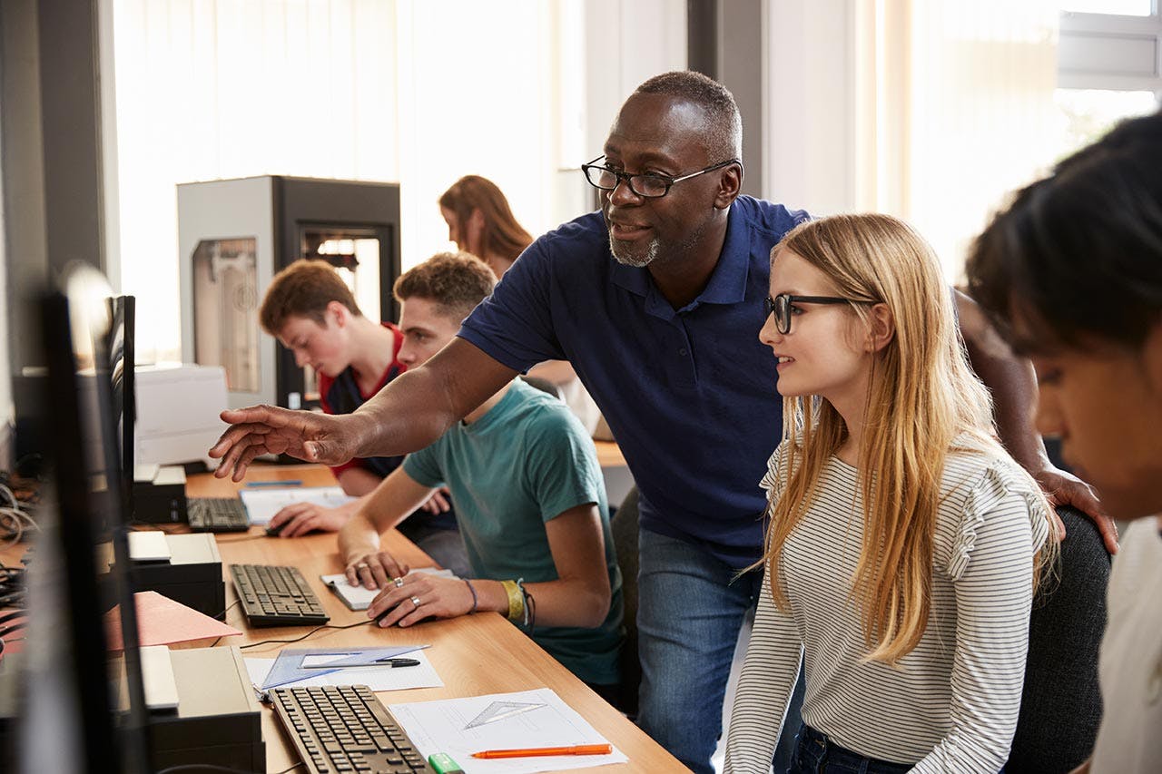 A student and teacher working on a computer