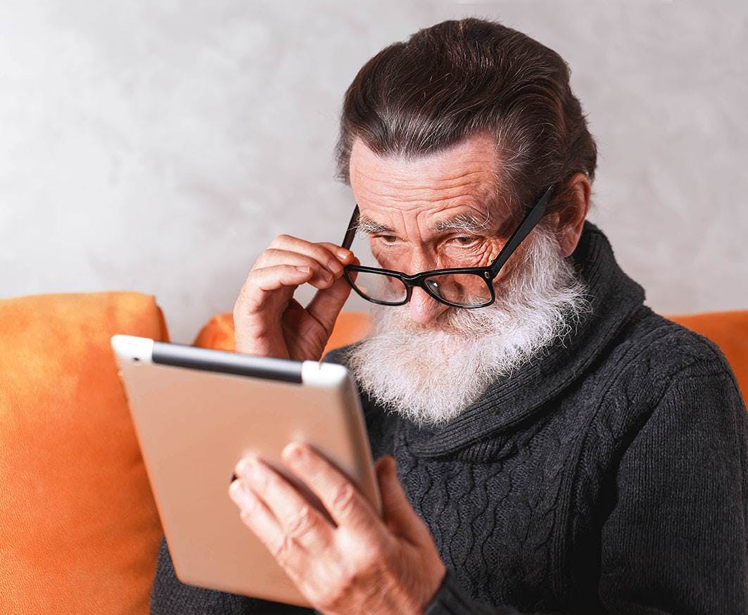 elderly man reading on a tablet