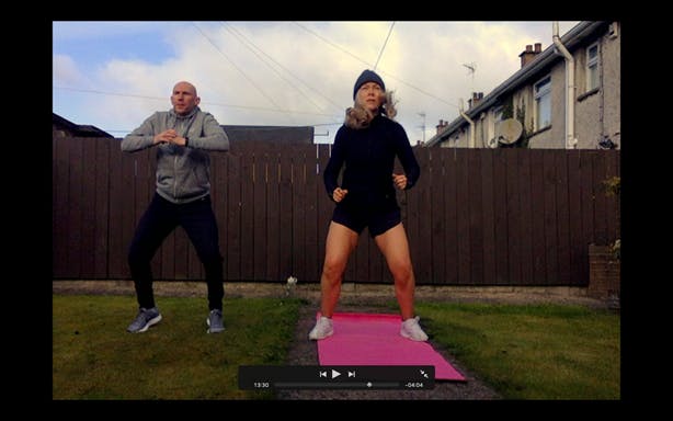 Angela and her partner Brian working out in their back garden, displayed on a laptop screen